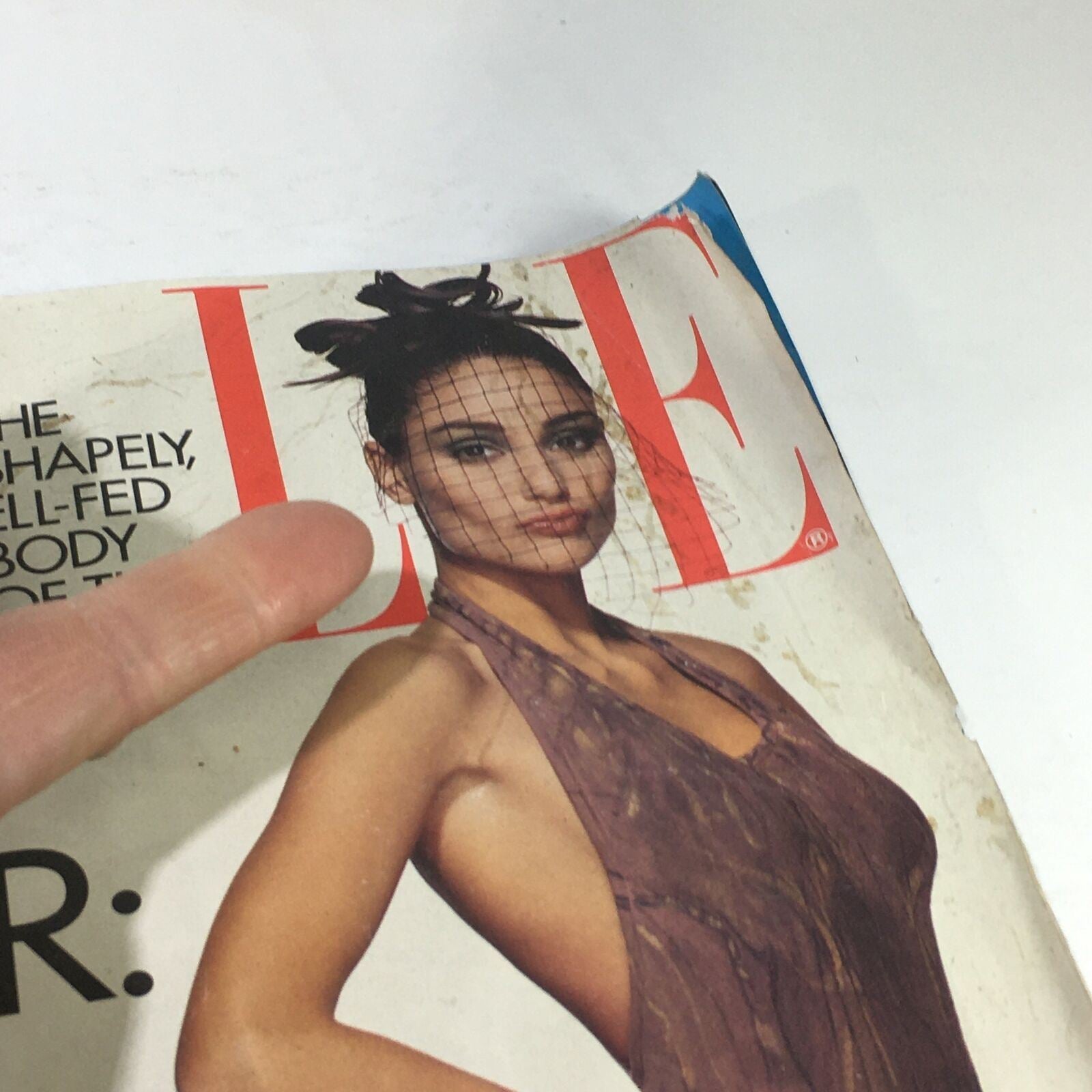 Close-up of the VTG Elle Magazine: February 1992 cover, featuring a model with a netted accessory on her head and a stylish dress, emphasizing the magazine's focus on spring fashion trends.