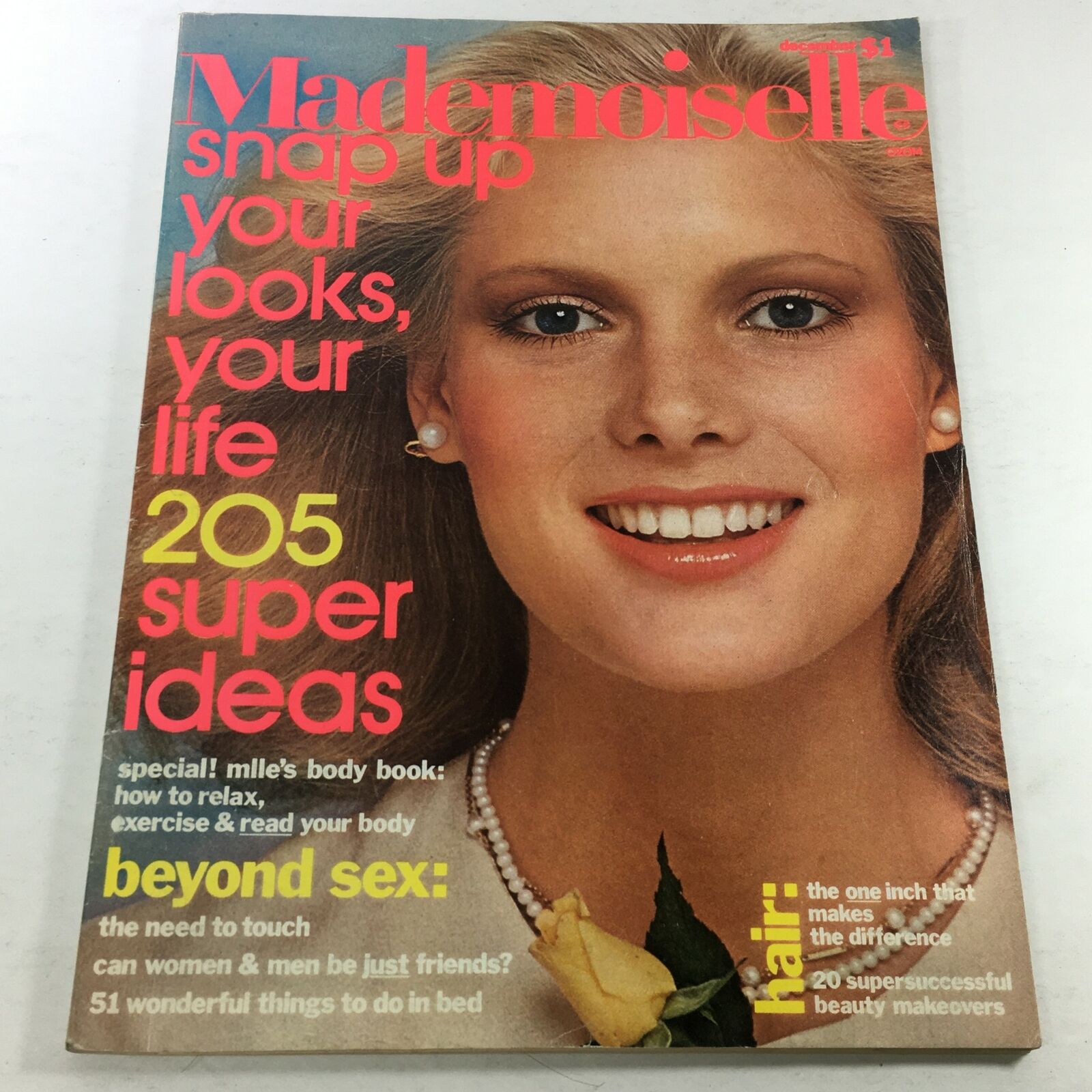 Cover of VTG Mademoiselle Magazine: December 1975 featuring a model with a bright smile, wearing pearl earrings and a floral accent, highlighting fashion trends and lifestyle content of the 1970s.