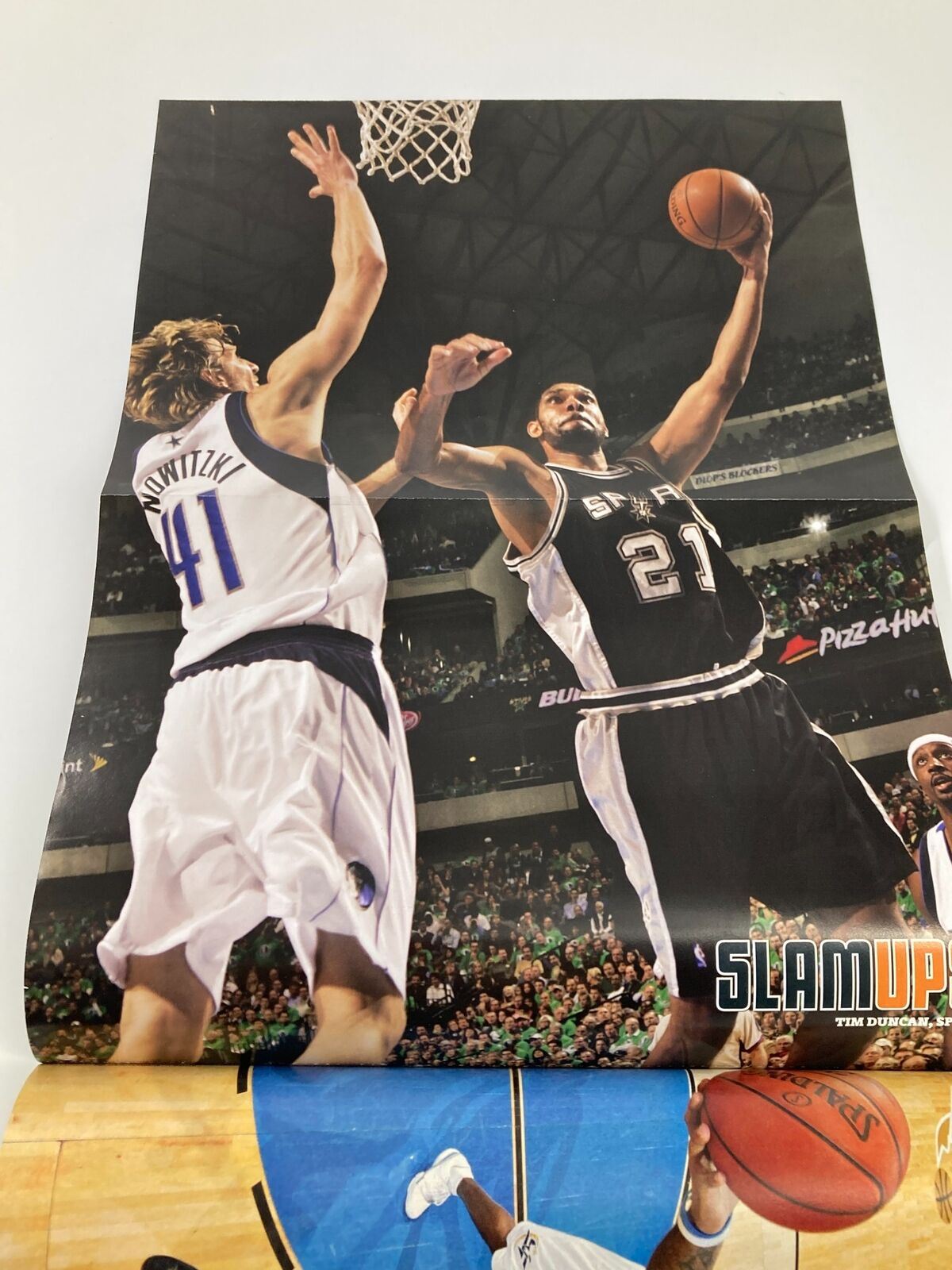 Slam Magazine March 2008 NBA poster featuring Tim Duncan in action against Dirk Nowitzki, illustrating the competitive spirit of the NBA.