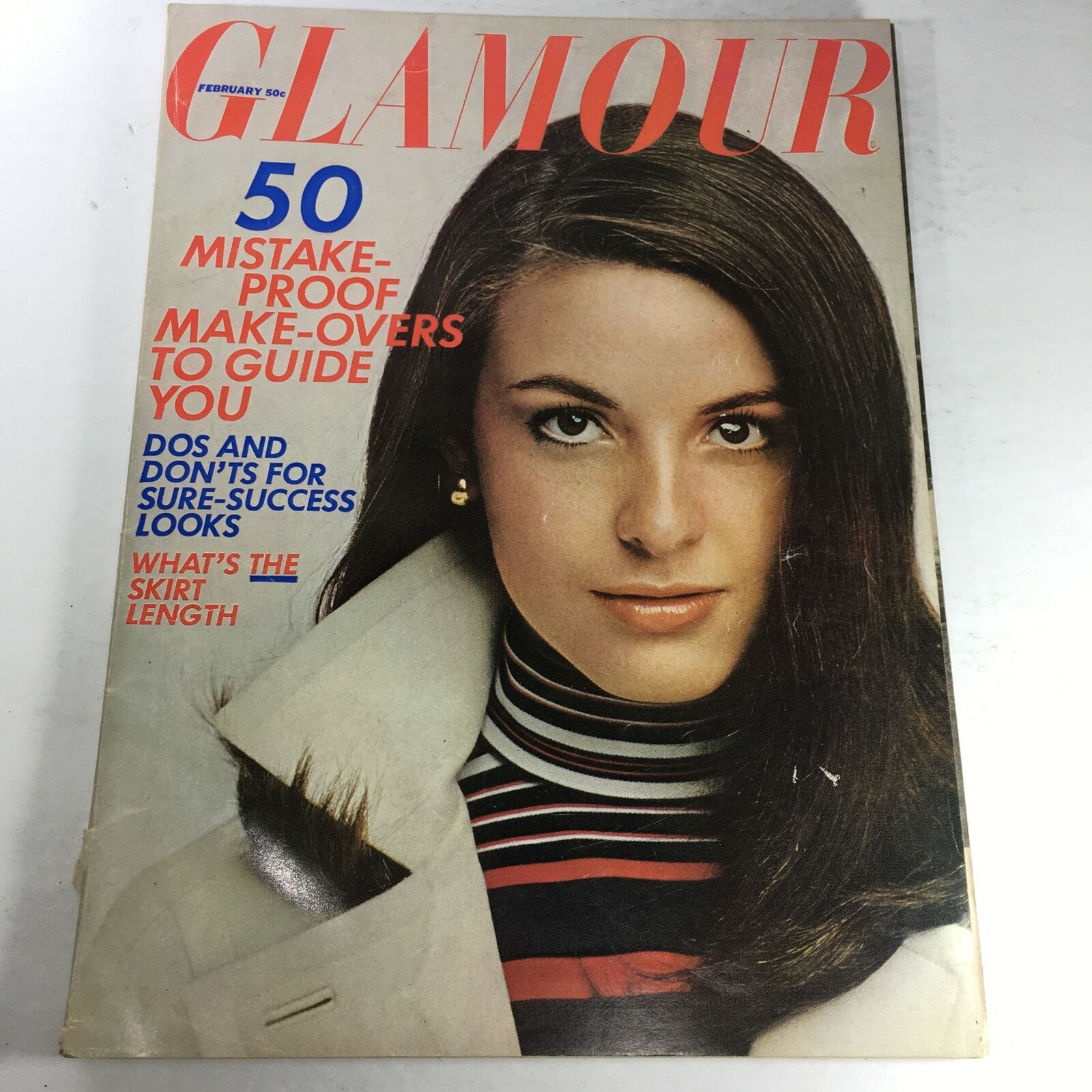 Cover image of VTG Glamour Magazine: February 1967 featuring a fashion model with long hair wearing a striped top and a white coat. The magazine discusses style tips and includes the headline '50 Mistake-Proof Make-Overs to Guide You.'