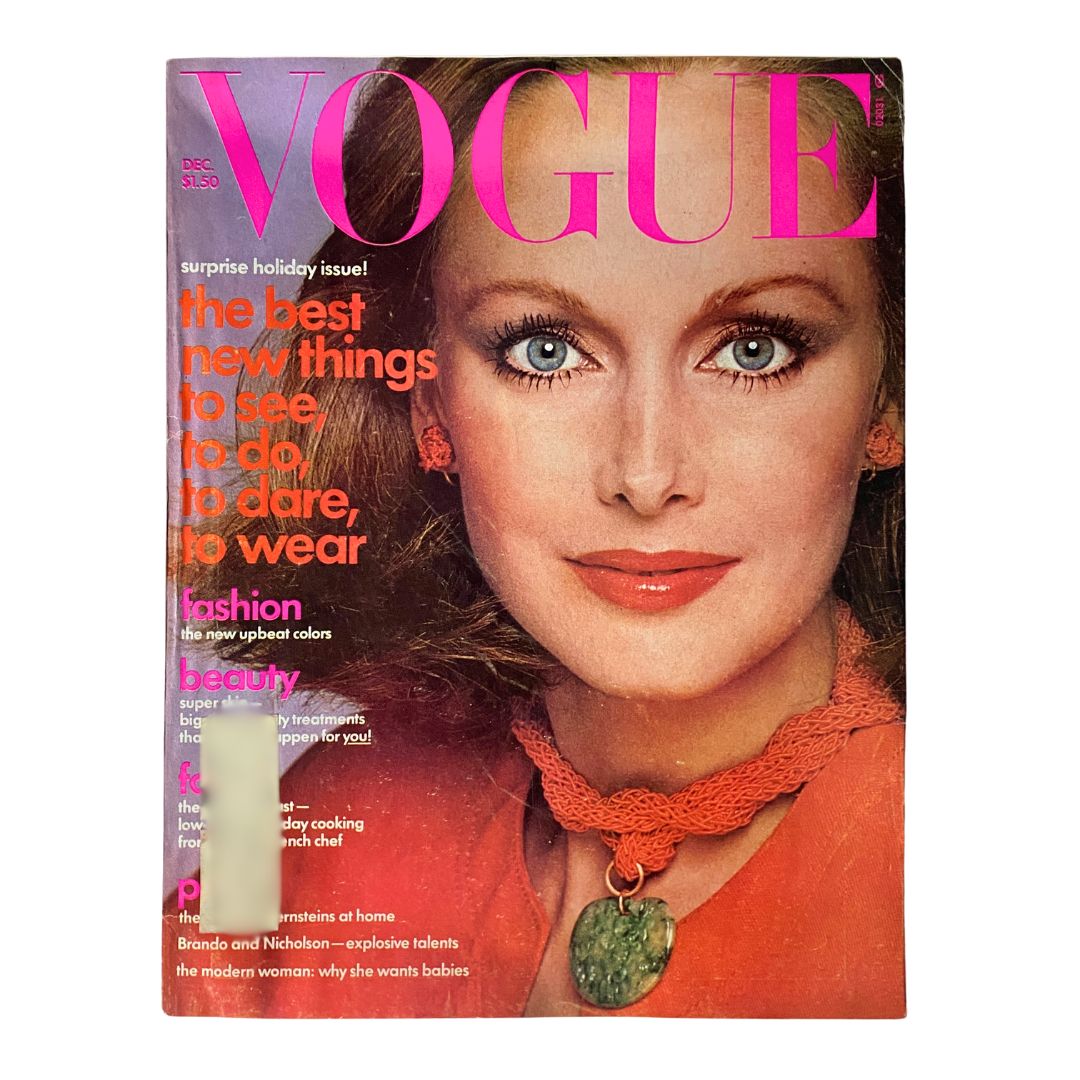 Cover of VTG Vogue Magazine December 1975 featuring model with striking blue eyes and vibrant red lipstick in a holiday-themed design.
