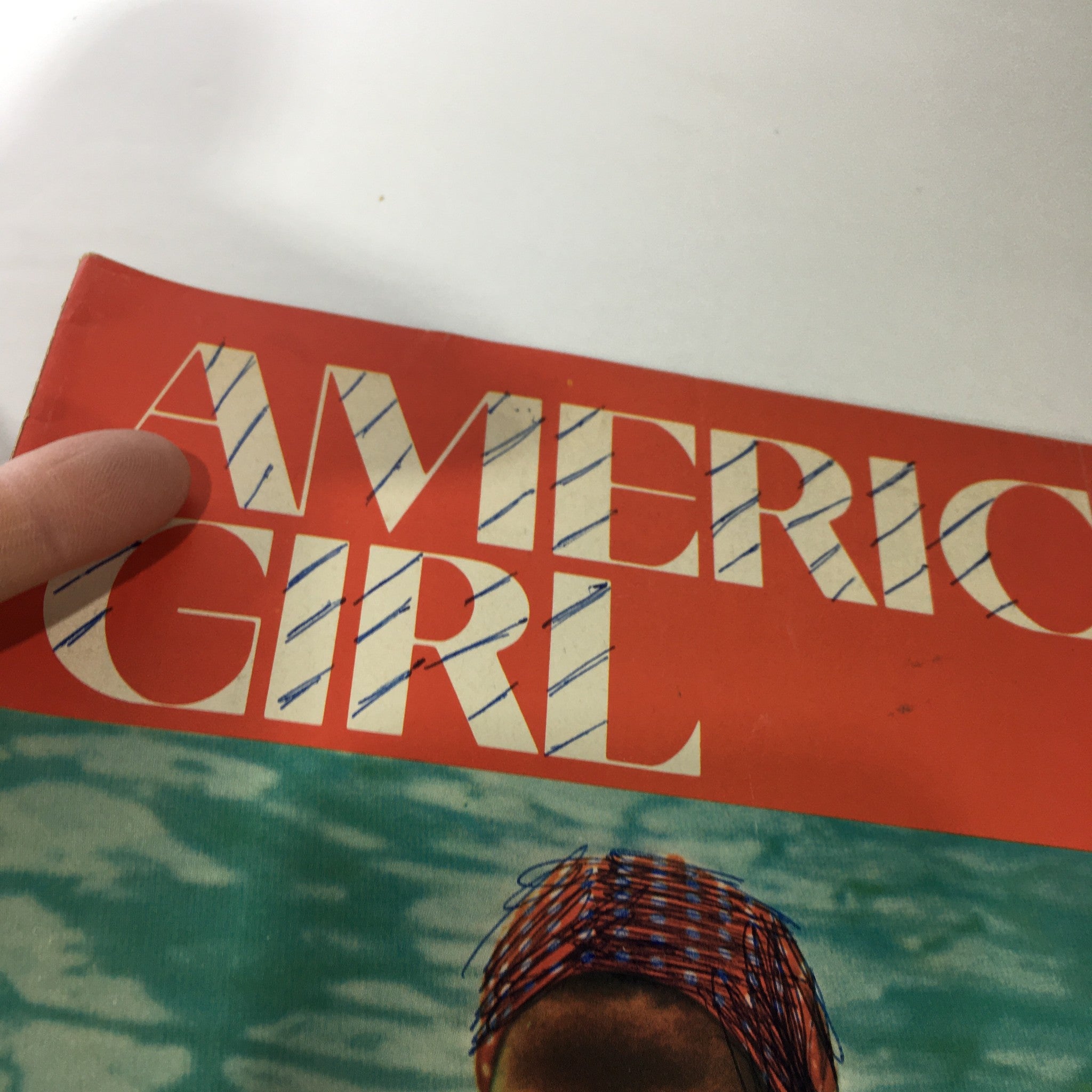 Close-up of the title text on the cover of VTG American Girl Magazine: July 1975, showcasing the bold lettering and vibrant color scheme.