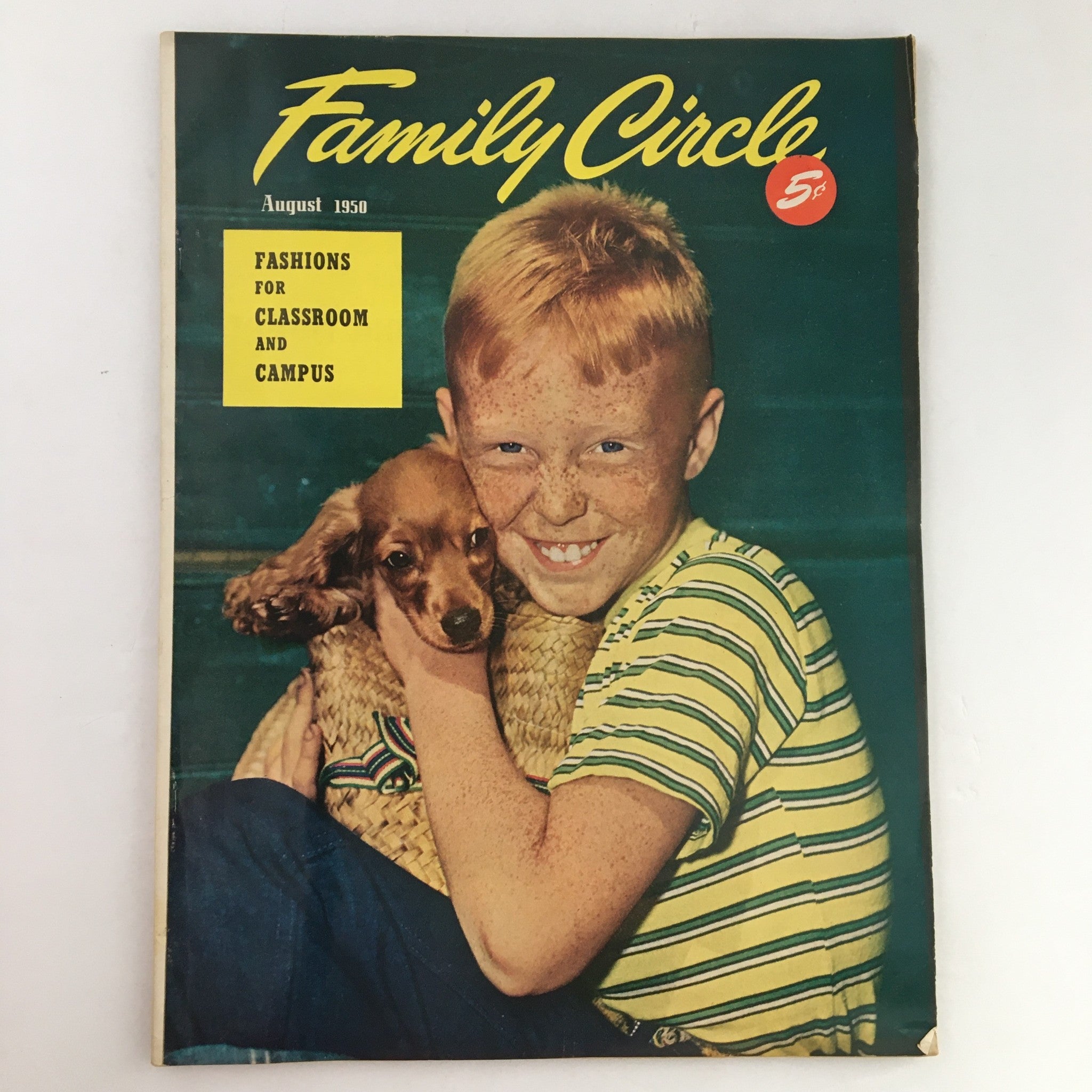 Cover of The Family Circle Magazine from August 1950, featuring a smiling boy with freckles holding a dog, highlighting fashions for classroom and campus.