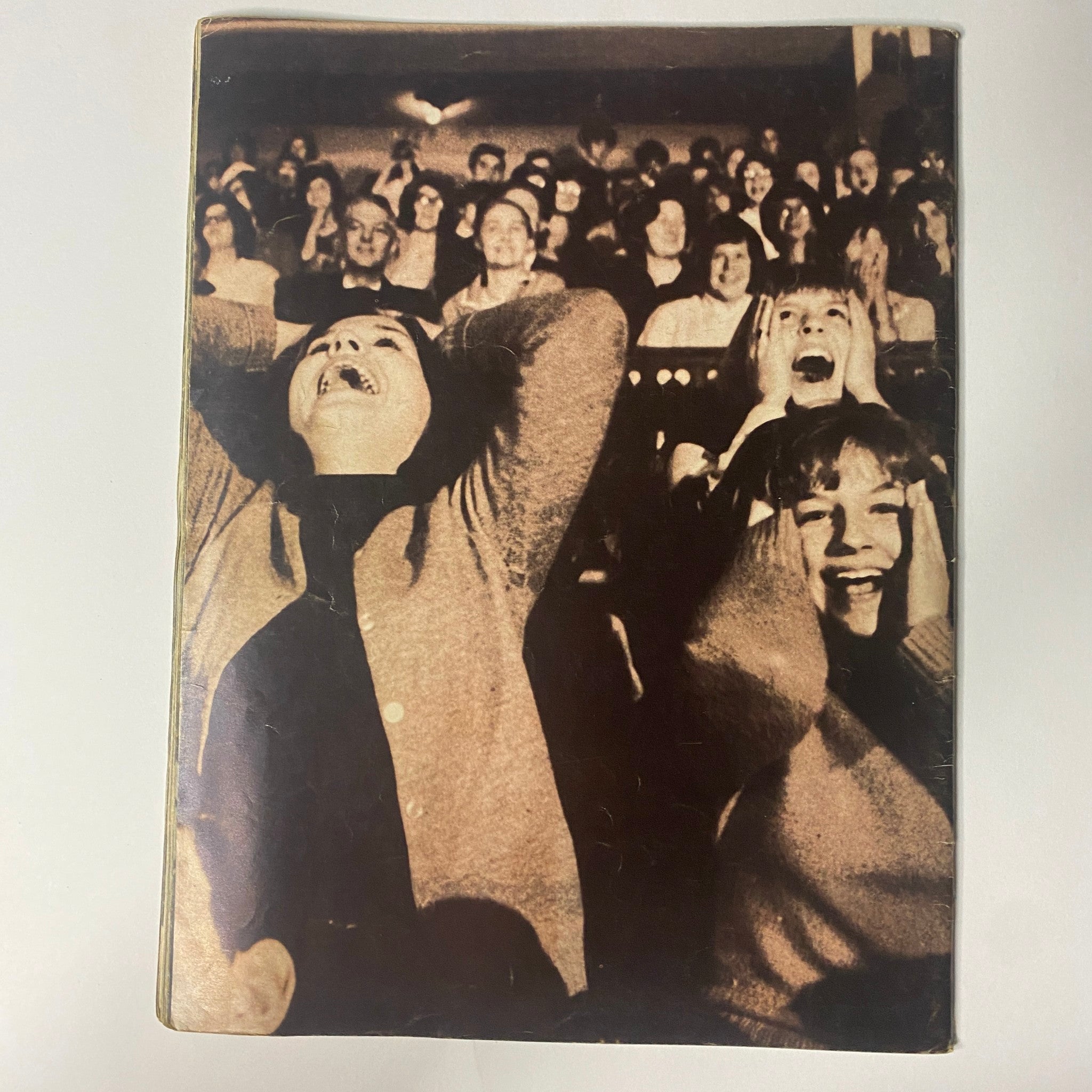 1964 The Original Beatles Book cover image depicting enthusiastic fans with their hands on their heads, expressing excitement and joy during a Beatles concert, capturing the essence of the cultural phenomenon known as Beatlemania.