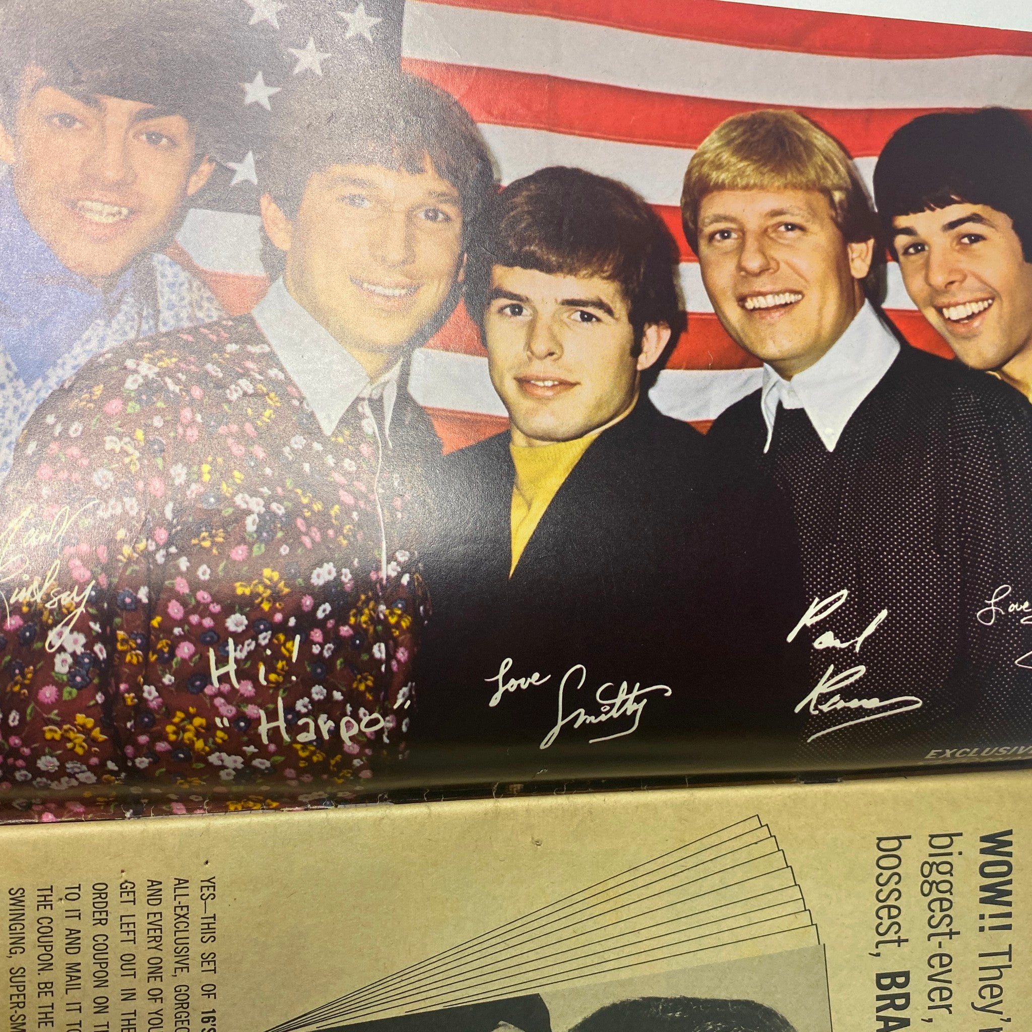 Image of Paul Revere & The Raiders with autographs, taken against a backdrop of an American flag, featured in 16 Magazine November 1966 Vol 8 No. 6.