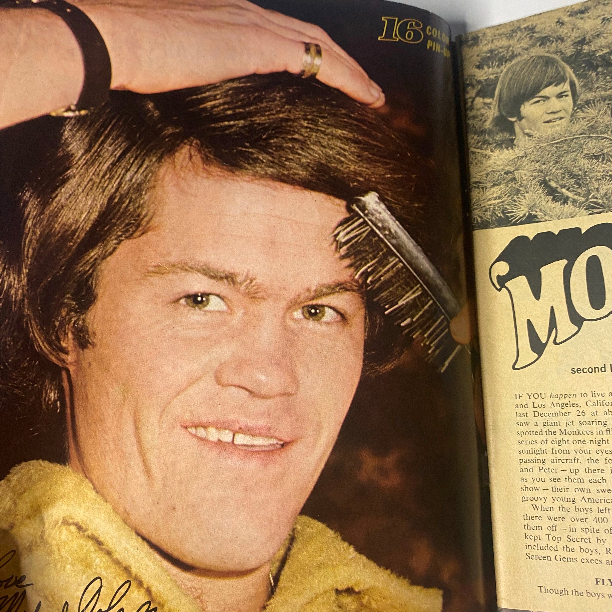 Close-up image of Micky Dolenz, featured in 16 Magazine May 1967 Vol 8 No. 12, smiling while grooming his hair with a comb.