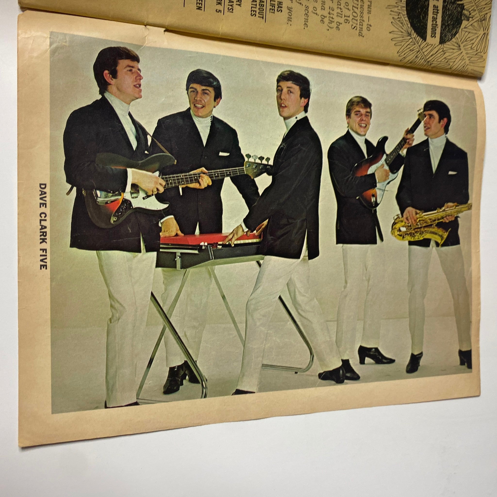 Color image of The Dave Clark Five as featured in 16 Magazine January 1965 Vol 6 No 8. The band members are posing with their instruments in stylish outfits, embodying the musical energy of the 1960s.