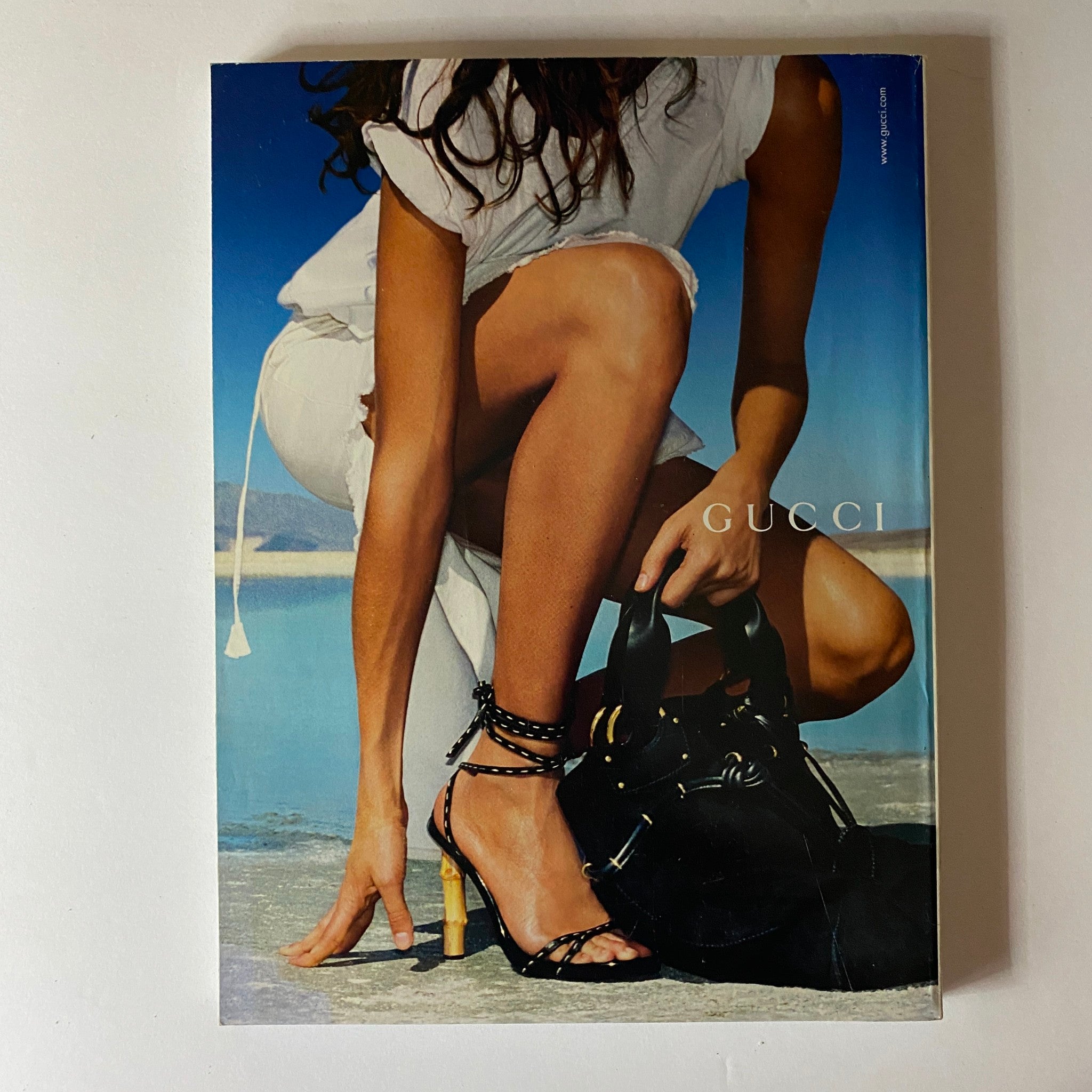 Back cover of Elle Magazine March 2002 featuring a stylish model in a white dress with a Gucci bag, capturing luxury fashion elements of the early 2000s.
