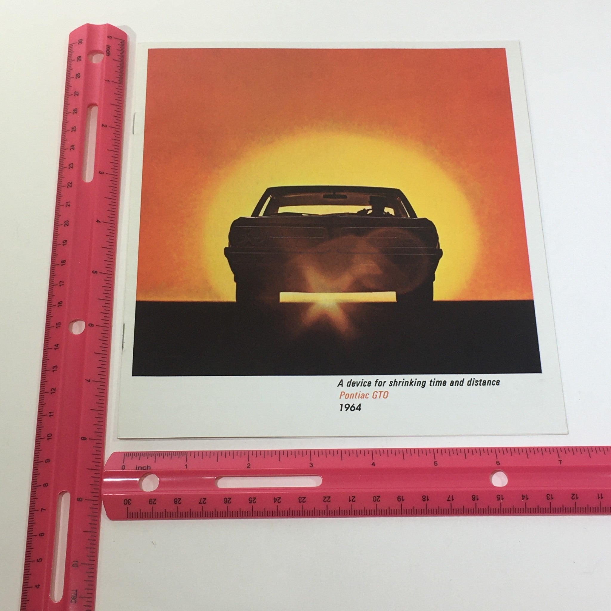 1964 Pontiac GTO catalog cover featuring a silhouette of the car against a sunset, showcasing the iconic design of this classic American muscle car.