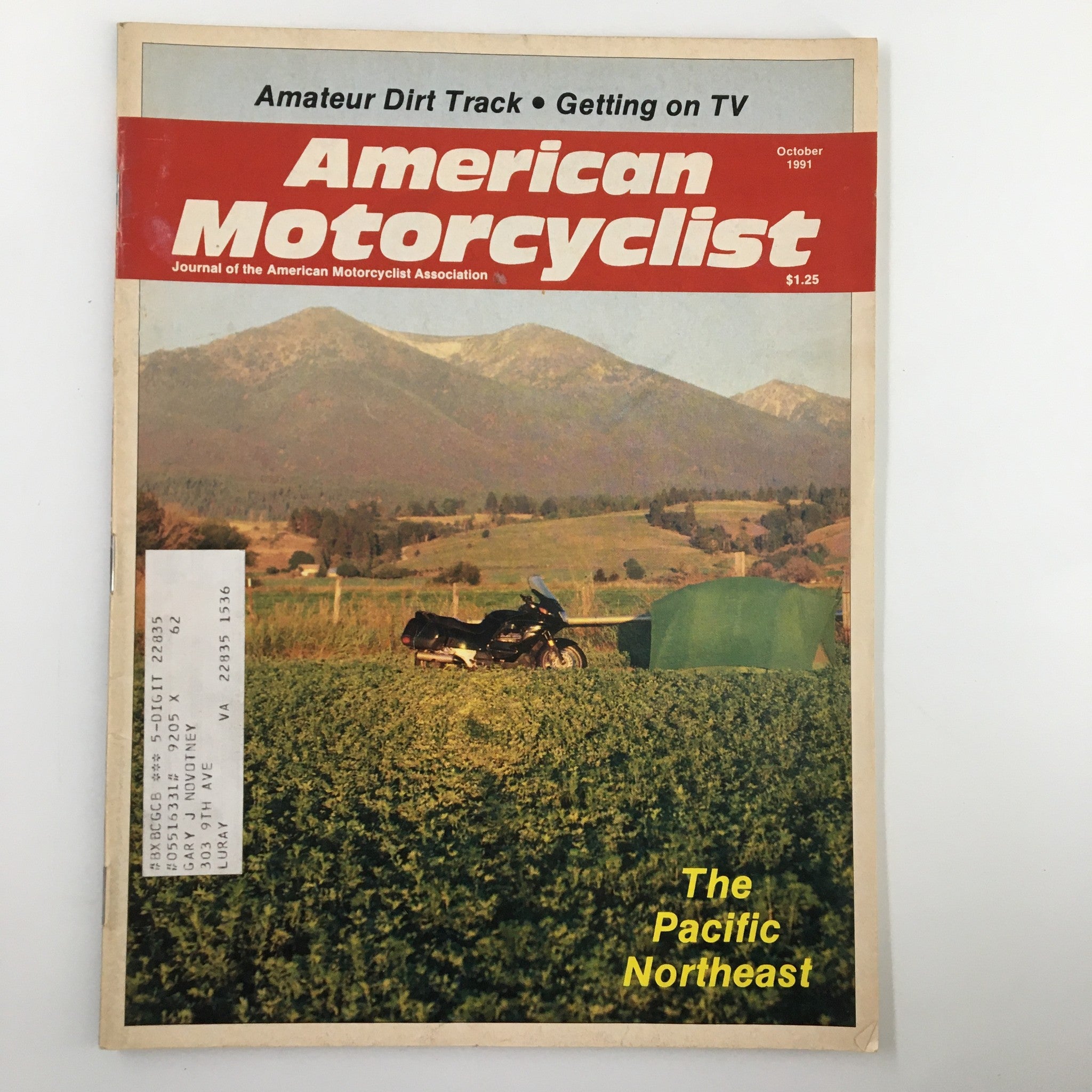 Cover of American Motorcyclist Magazine October 1991 featuring a motorcycle in the Pacific Northeast landscape, showcasing vibrant photography and vintage motorcycling culture.