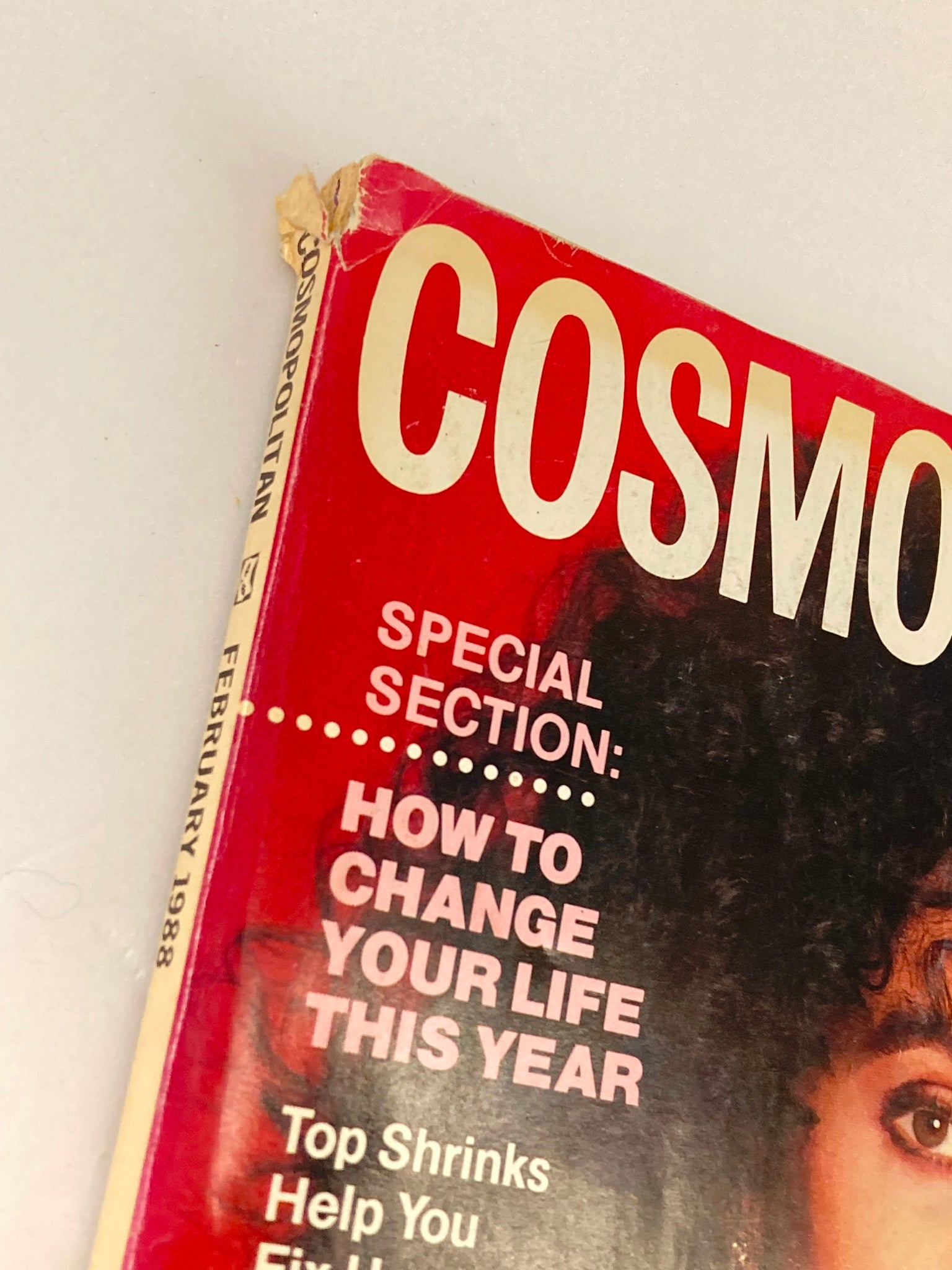 Close-up of the spine and top corner of the VTG Cosmopolitan Magazine February 1988 cover featuring Cher, highlighting minor wear and vintage aesthetic.