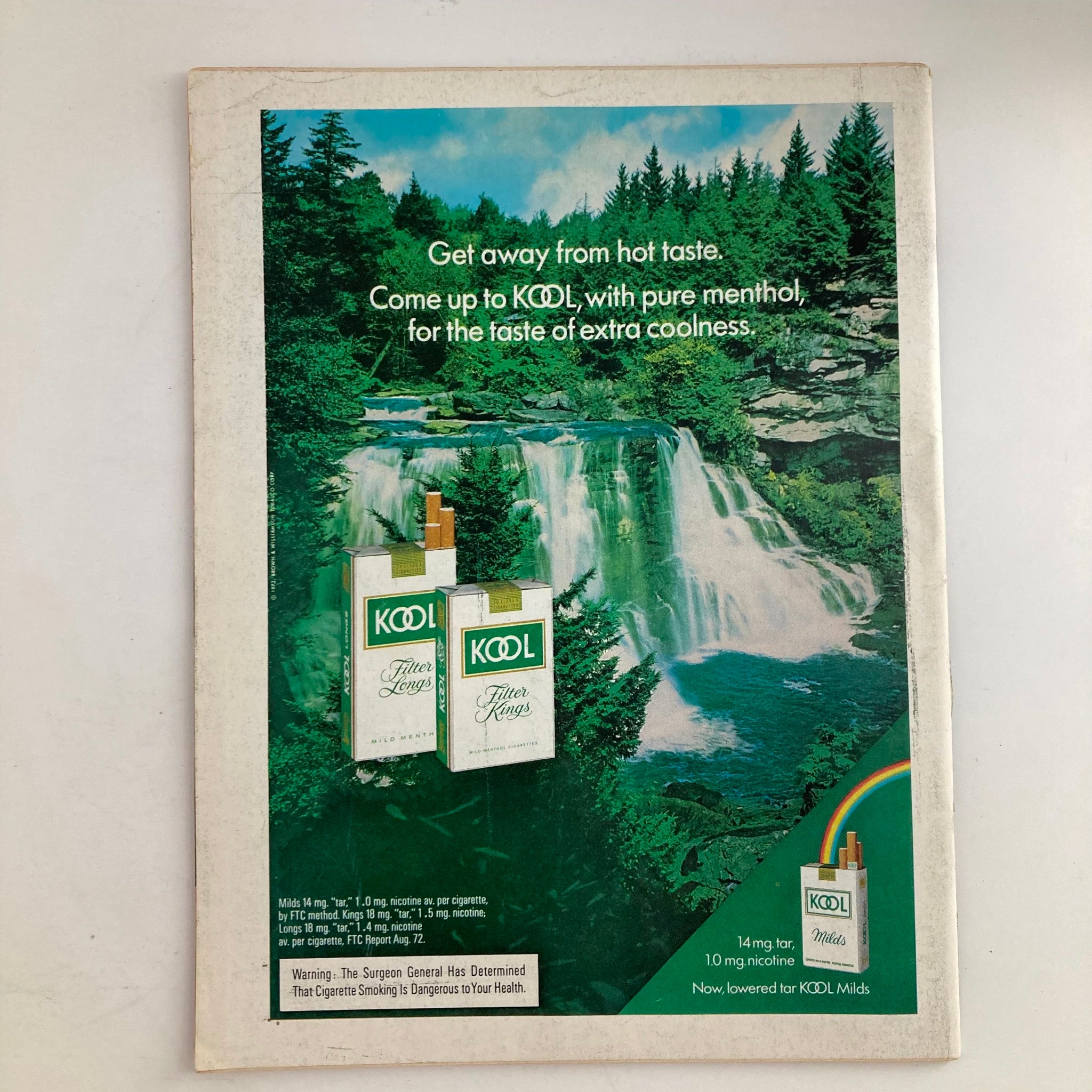 Vintage advertisement for KOOL cigarettes featuring a scenic waterfall background. The ad promotes the brand's menthol flavor with the tagline 'Get away from hot taste' on the cover of the VTG Newsweek Magazine from January 22, 1973.