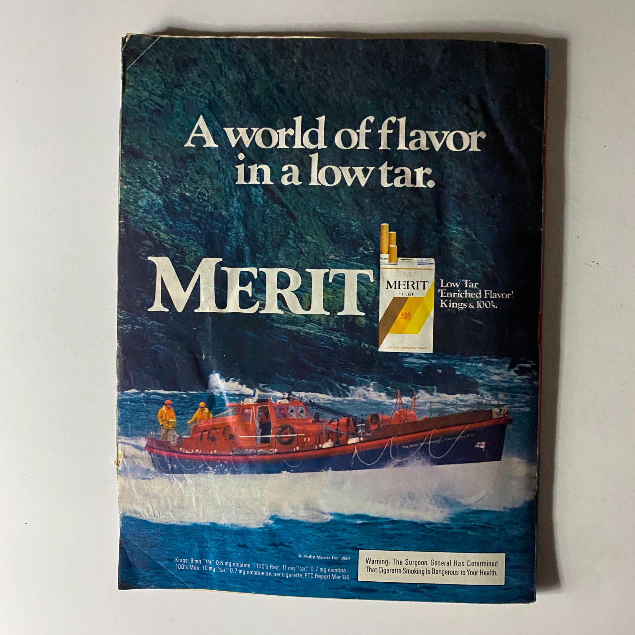 An advertisement for Merit cigarettes, depicting a scenic coastal view with a rescue boat, emphasizing 'A world of flavor in a low tar' from People Weekly Magazine September 3, 1984.