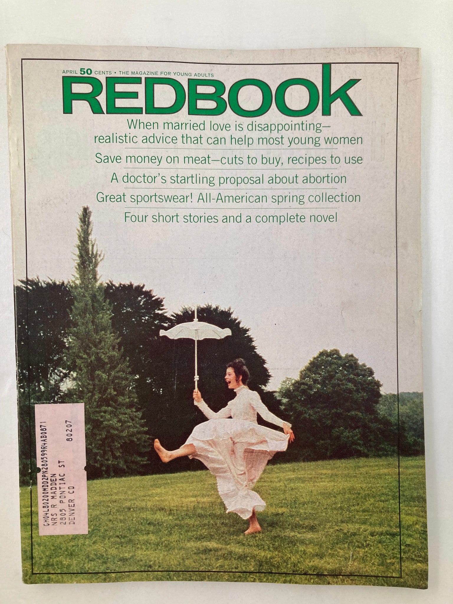 VTG Redbook Magazine April 1970 cover featuring a woman in a white dress joyfully holding an umbrella while standing in a lush green field, capturing the essence of spring and youthful spirit.