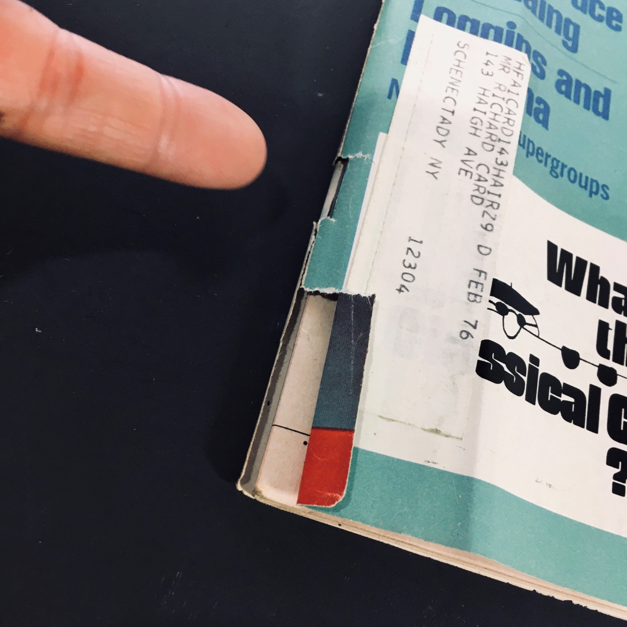 Close-up of the side of High Fidelity Magazine April 1973 with a label and finger pointing, highlighting details of its vintage wear.