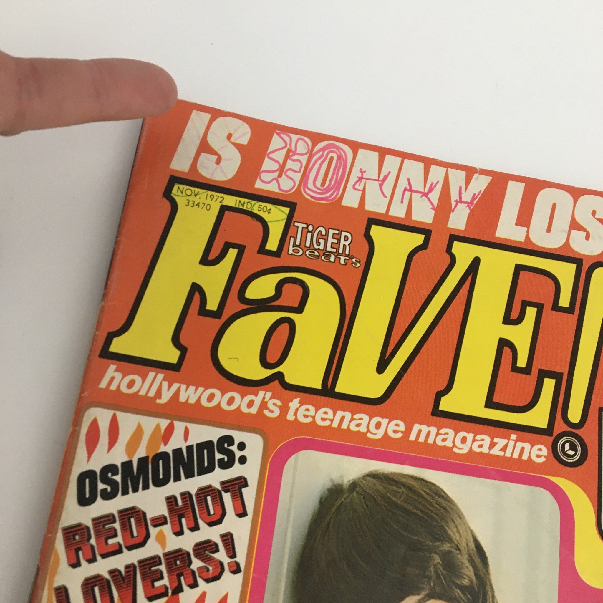 Close-up of Tiger Beats Fave Magazine November 1972 cover highlighting the title and features such as 'Is Donny Losing You?' with a finger pointing to the magazine details, emphasizing its vintage appeal.