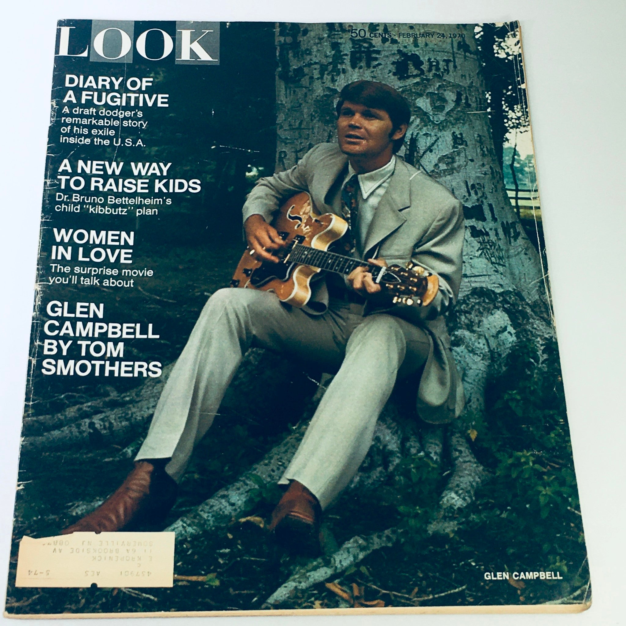Vintage Look Magazine cover from February 24, 1970 featuring Glen Campbell by Tom Smothers. The cover showcases Campbell in a formal suit, sitting against a tree while playing guitar, capturing the essence of 1970s pop culture.