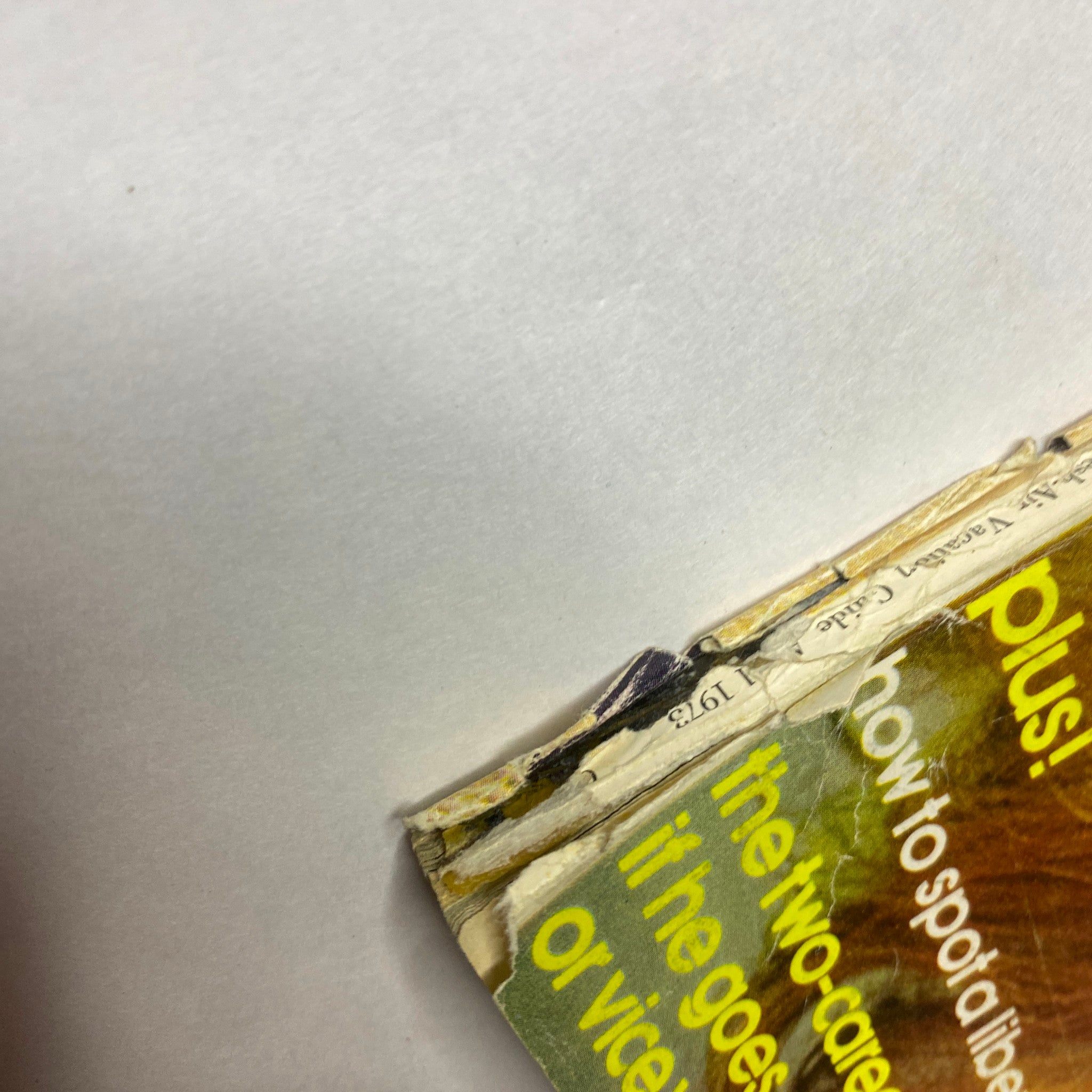 Angle shot of the spine of Mademoiselle Magazine April 1973, showing the aged texture and wear, emphasizing the magazine's vintage appeal.