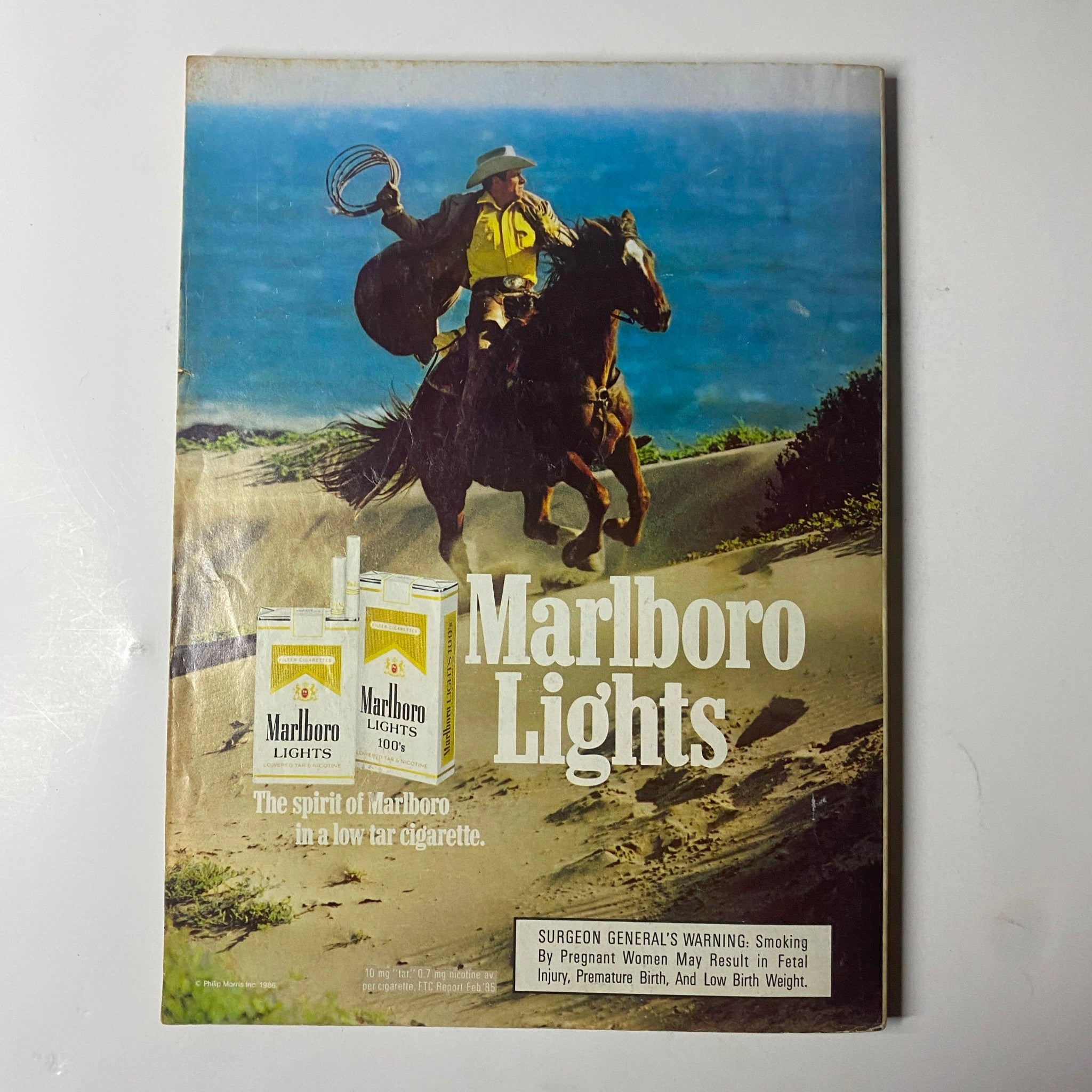 Marlboro Lights advertisement featuring a cowboy on horseback in a scenic desert landscape, found in the July 1986 Cosmopolitan Magazine with Paulina Porizkova cover.