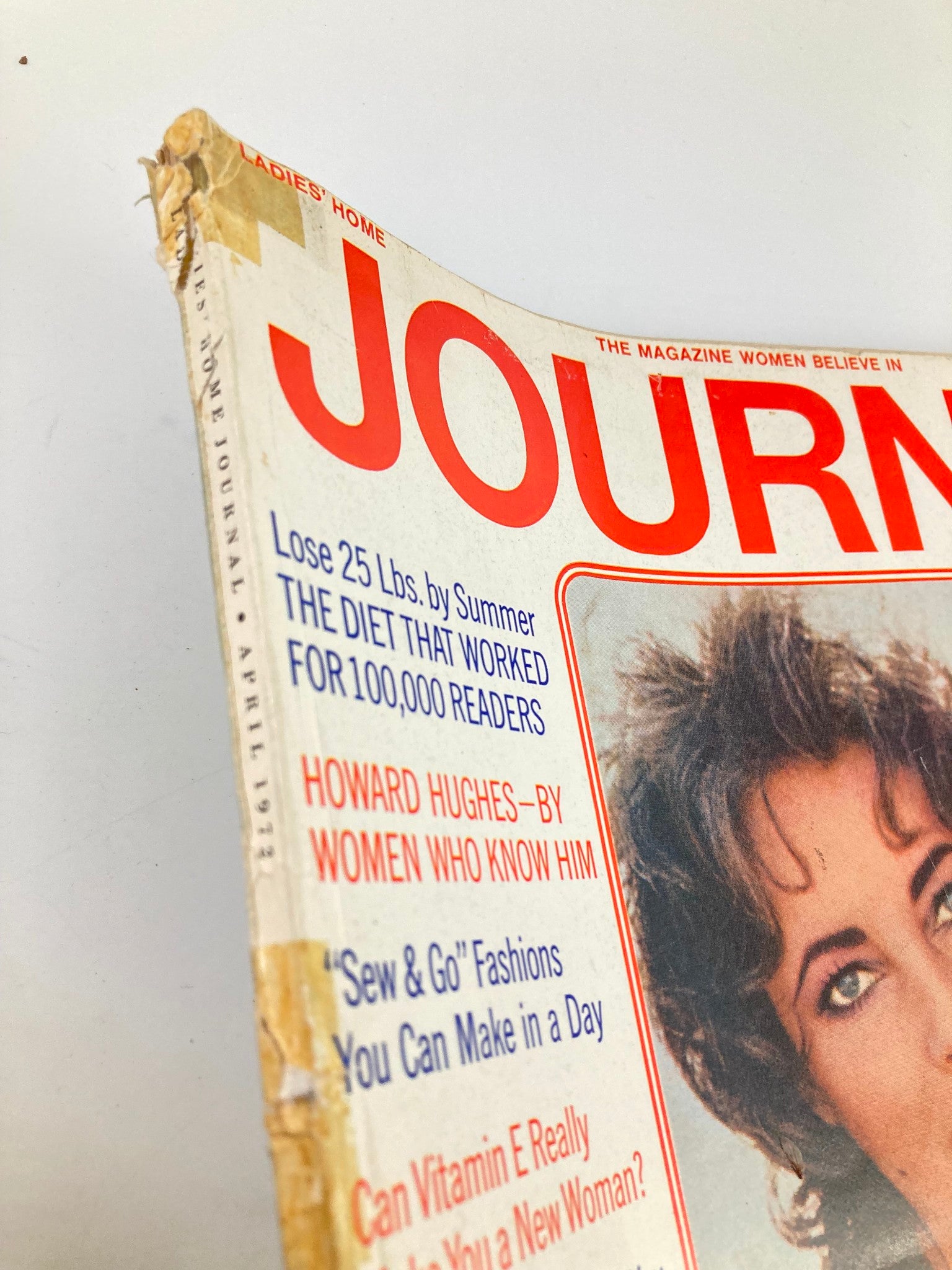 Close-up image of the edge of the April 1972 Ladies' Home Journal magazine cover, featuring Elizabeth Taylor. The image shows the wear and tear typical of vintage collectibles, with visible damage on the corner and side, emphasizing its authenticity and historical significance.