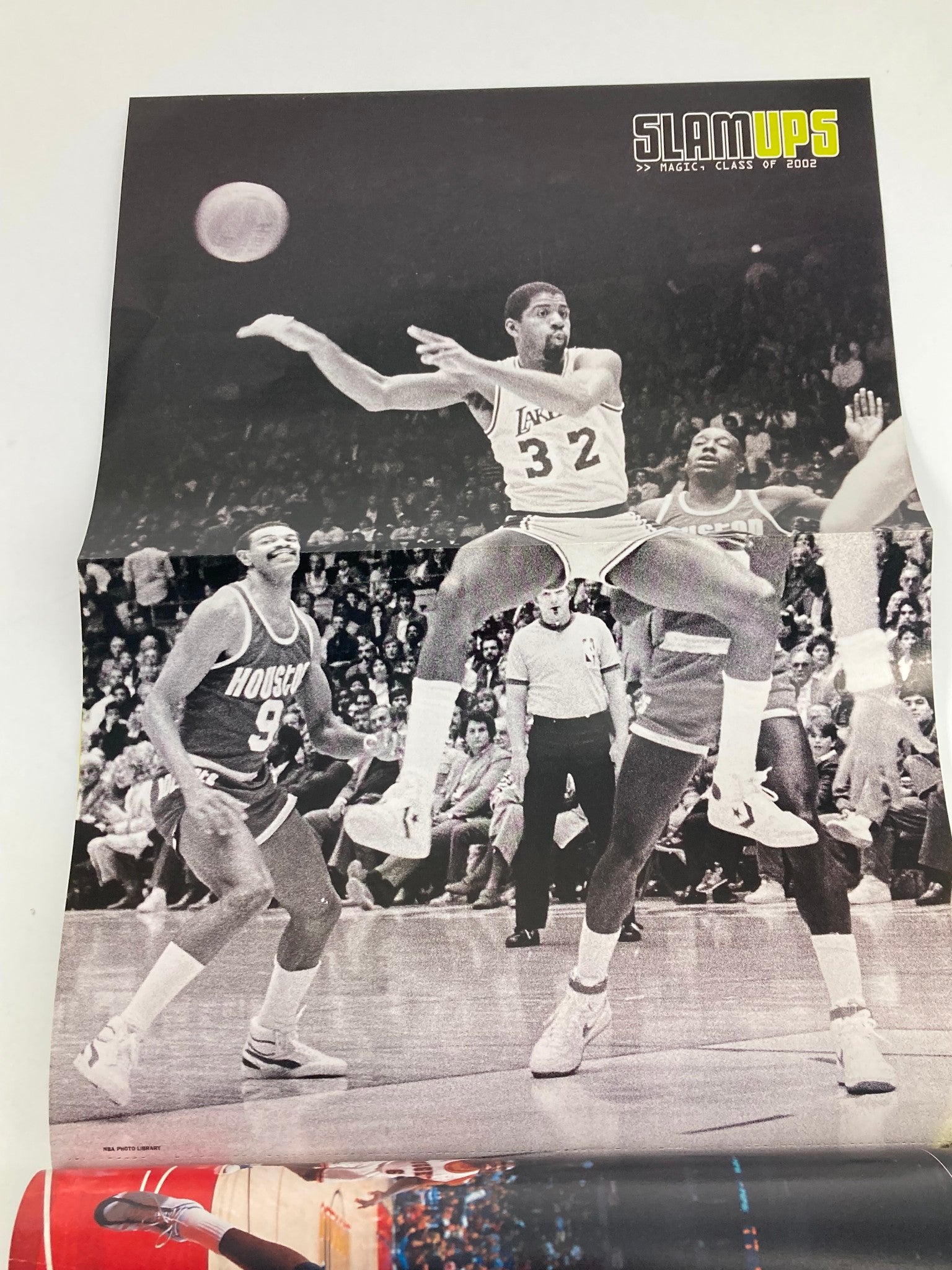 Vintage Slam Magazine December 2002 poster featuring a thrilling basketball action shot showcasing player number 32 of the Lakers, amid two opponents, part of the Amar'e Stoudemire and Caron Butler issue. This collectible item highlights the excitement of early 2000s basketball culture.