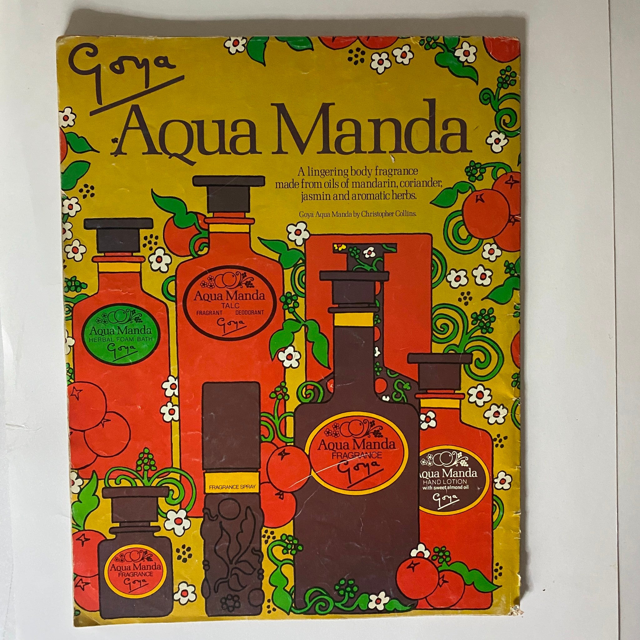 Cover of Goya Aqua Manda, a vintage body fragrance promotional advertisement highlighting a colorful design with various fragrance bottles and the tagline describing the lingering scent made from natural oils, complemented by vibrant floral patterns.