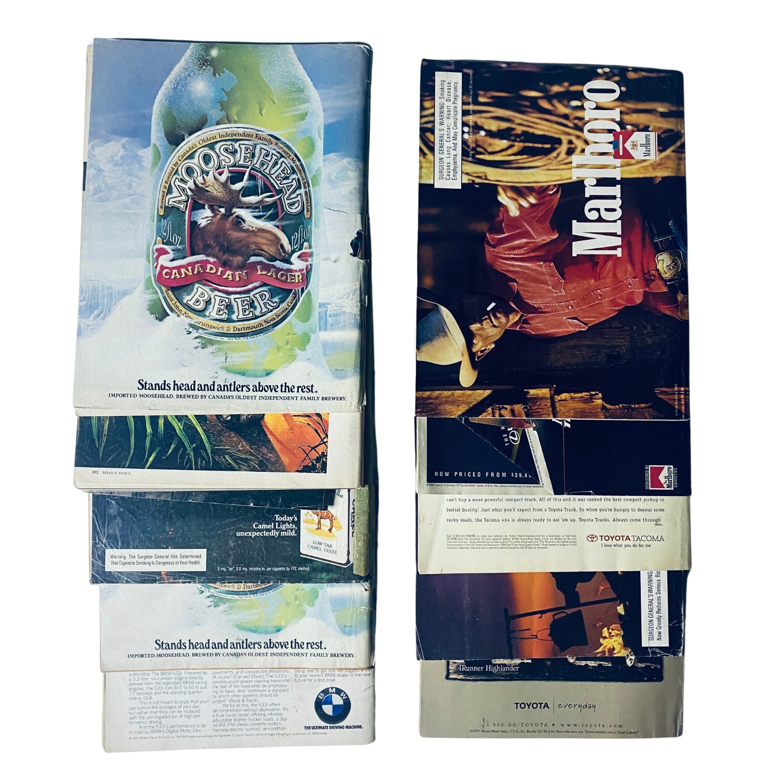 Stack of vintage advertising materials alongside a collection of Road & Track Magazines, emphasizing automotive culture and lifestyle.