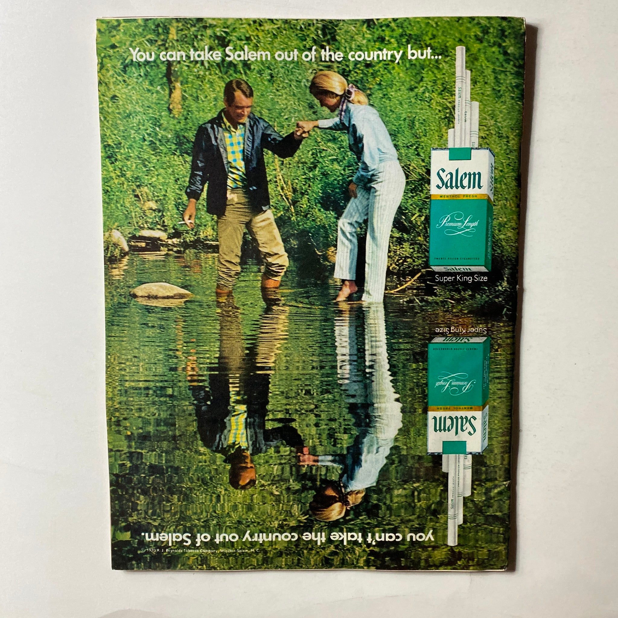 Vintage advertisement featuring two people by a creek, promoting Salem cigarettes with the tagline about taking Salem out of the country.