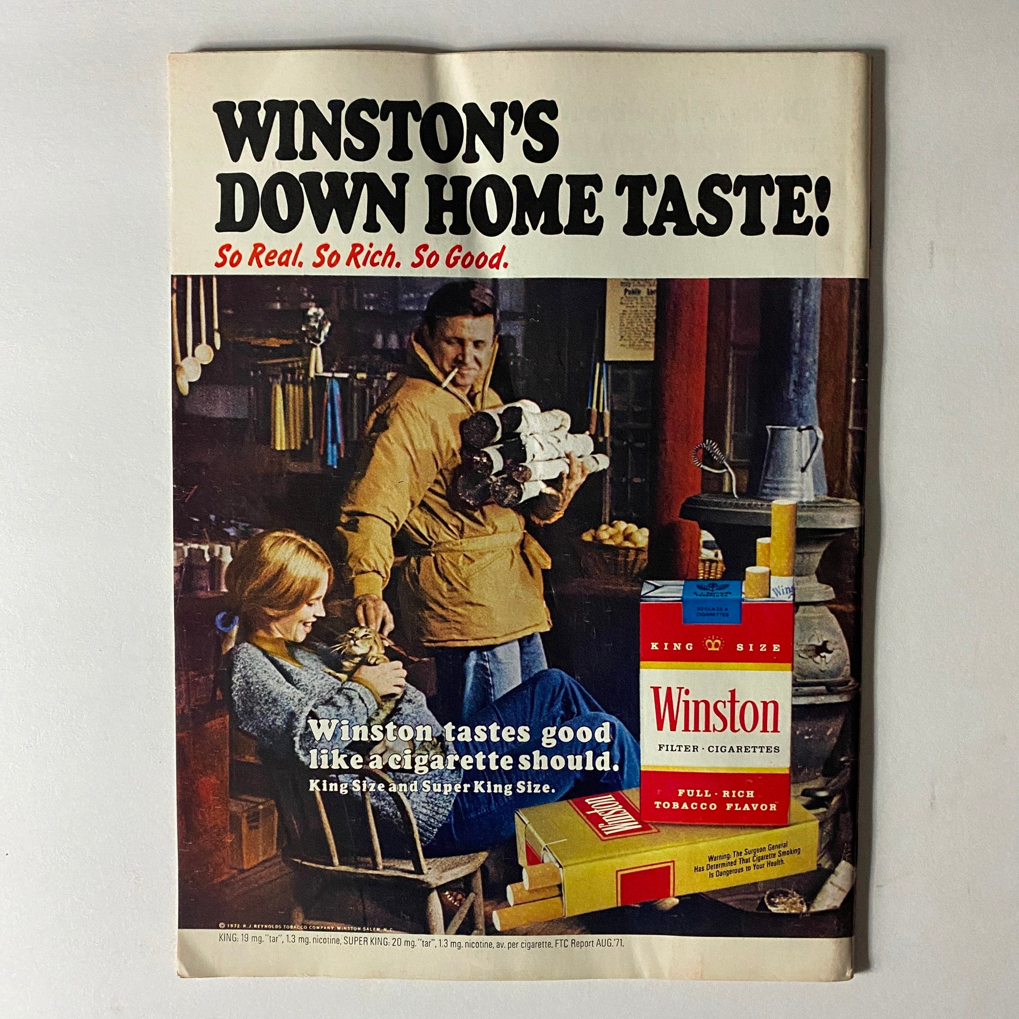 Vintage Winston cigarette advertisement showcasing a rustic setting with a man holding a stack of logs and a woman seated comfortably, featuring the tagline 'Winston tastes good like a cigarette should.' This image complements the VTG Time Magazine January 31, 1972 highlighting comedian Flip Wilson, known as the first Black superstar of television.