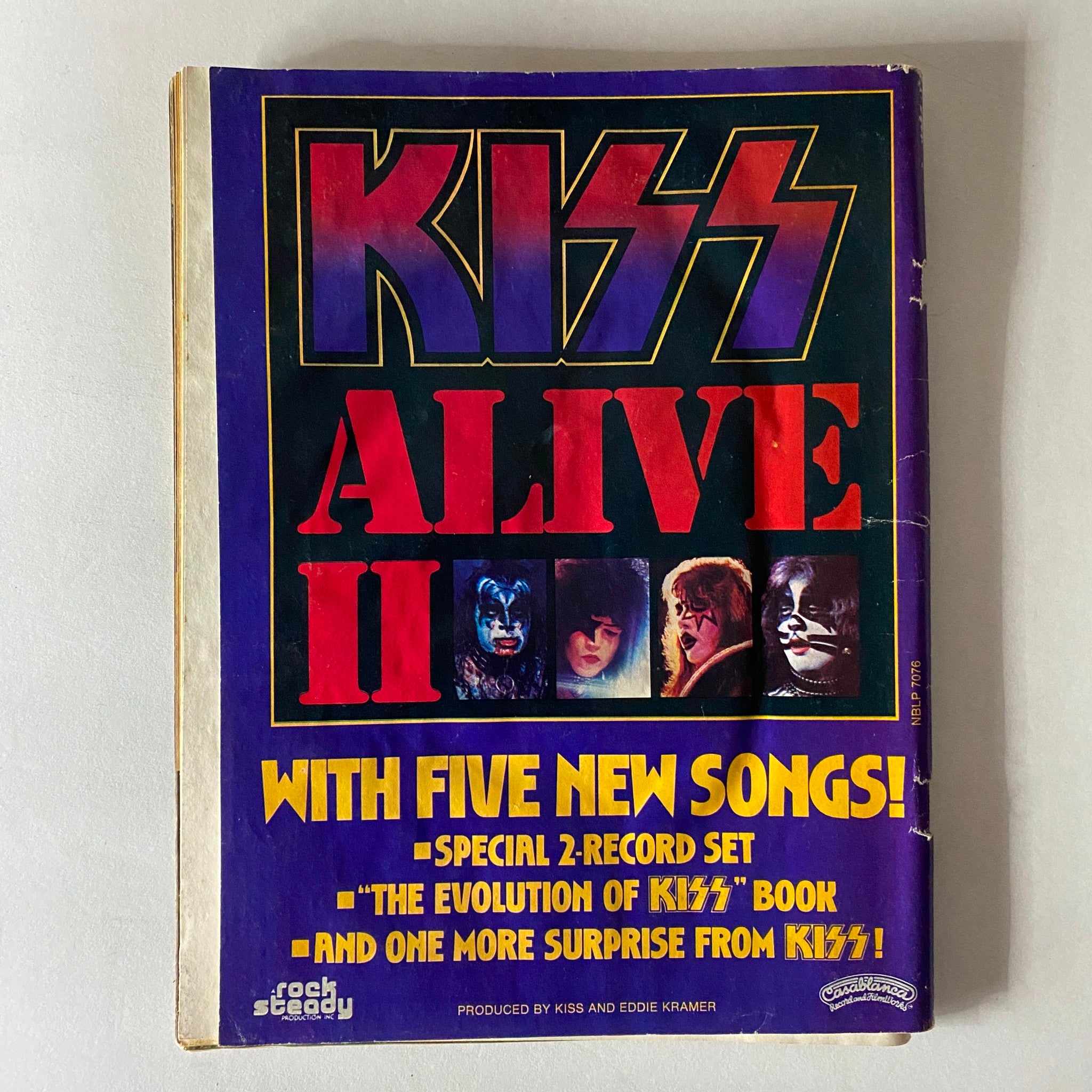 Cover page of Kiss Alive II album featuring colorful designs and band member images, highlighting new songs and special features.