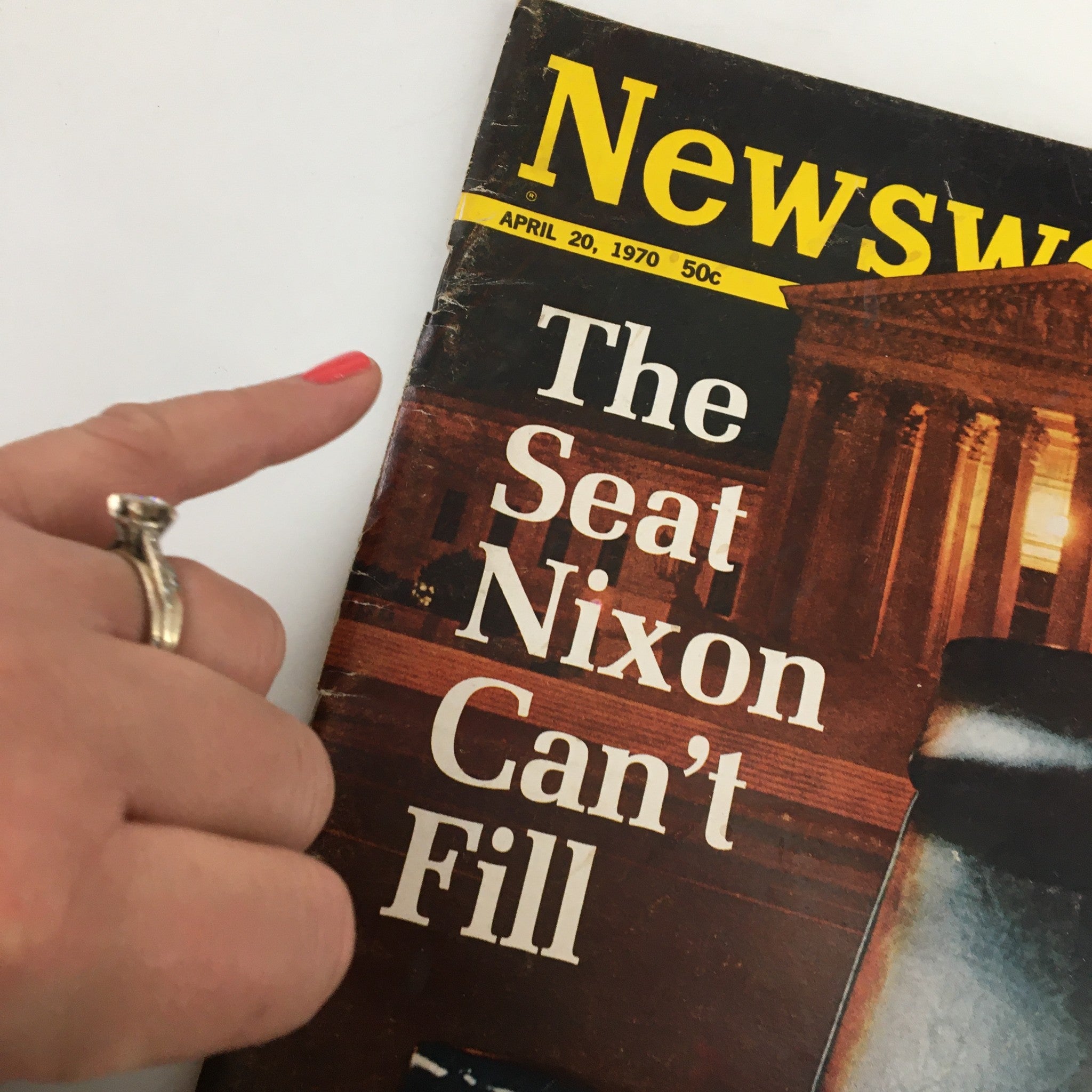 Close-up view of a hand indicating the title on the vintage Newsweek magazine cover 'The Seat Nixon Can't Fill', dated April 20, 1970.