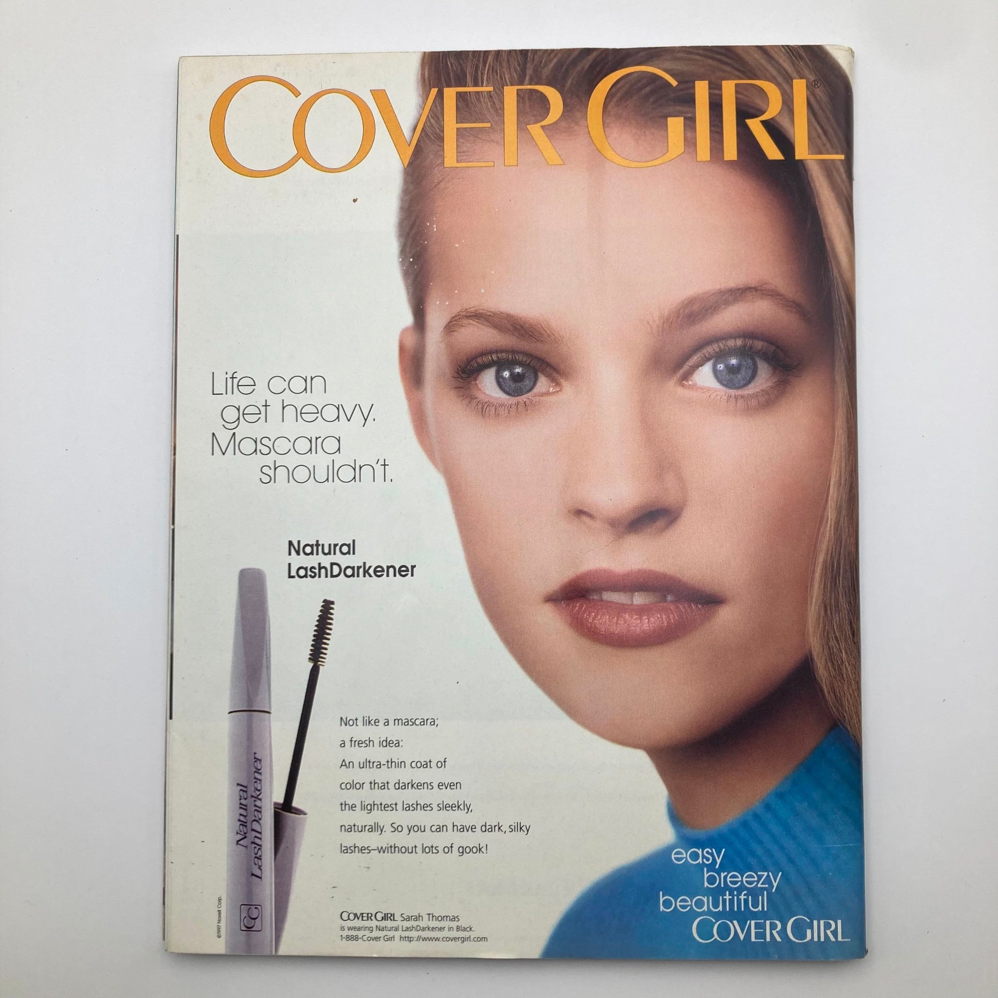 Vintage Cover Girl advertisement highlighting Natural LashDarkener, promoting light and easy mascara application. Features an attractive model with bright eyes and a fresh look, set in an appealing layout.