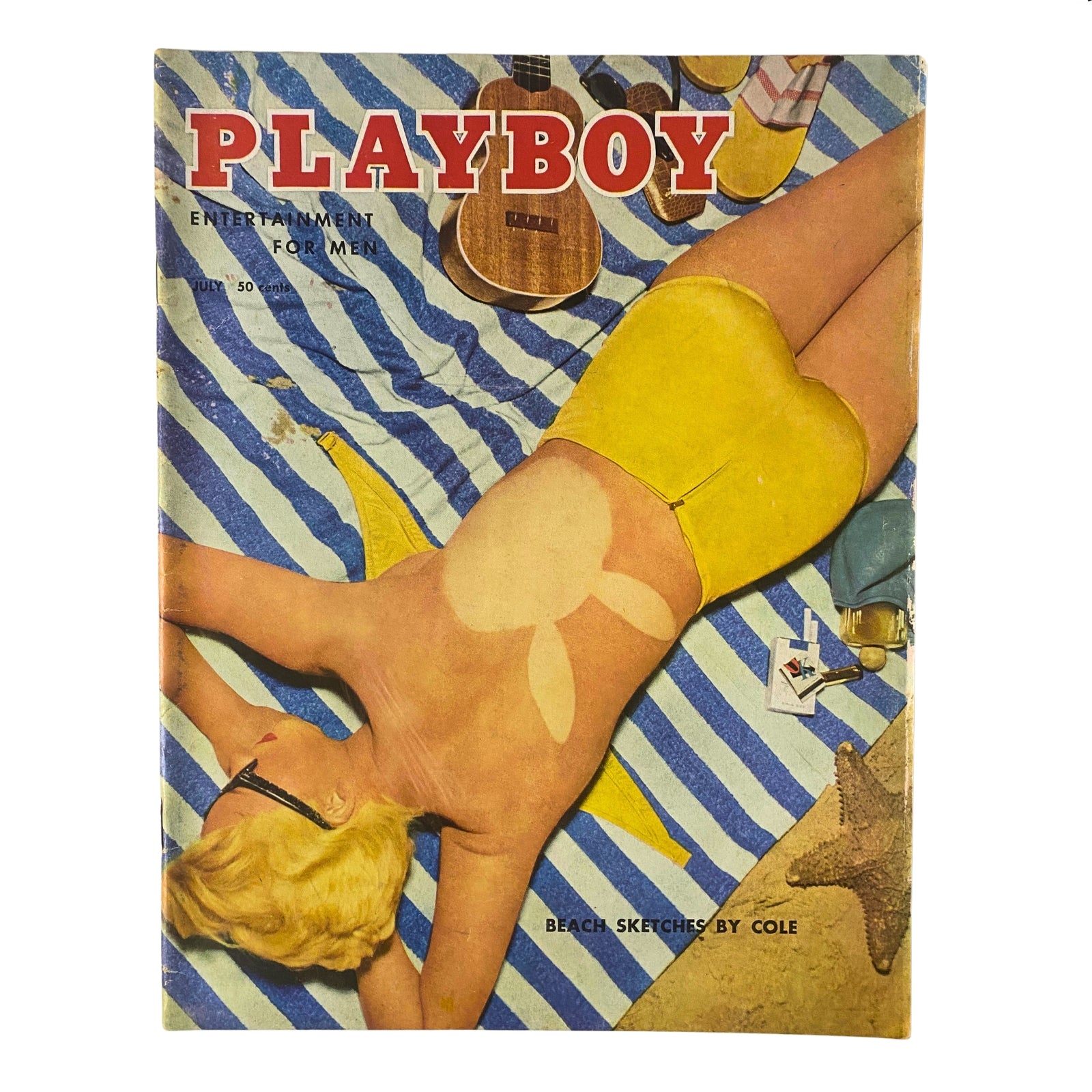 Cover of Playboy Magazine July 1955 featuring Playmate Janet Pilgrim laying on a beach towel, showcasing a retro design with a yellow swimsuit and playful background items.