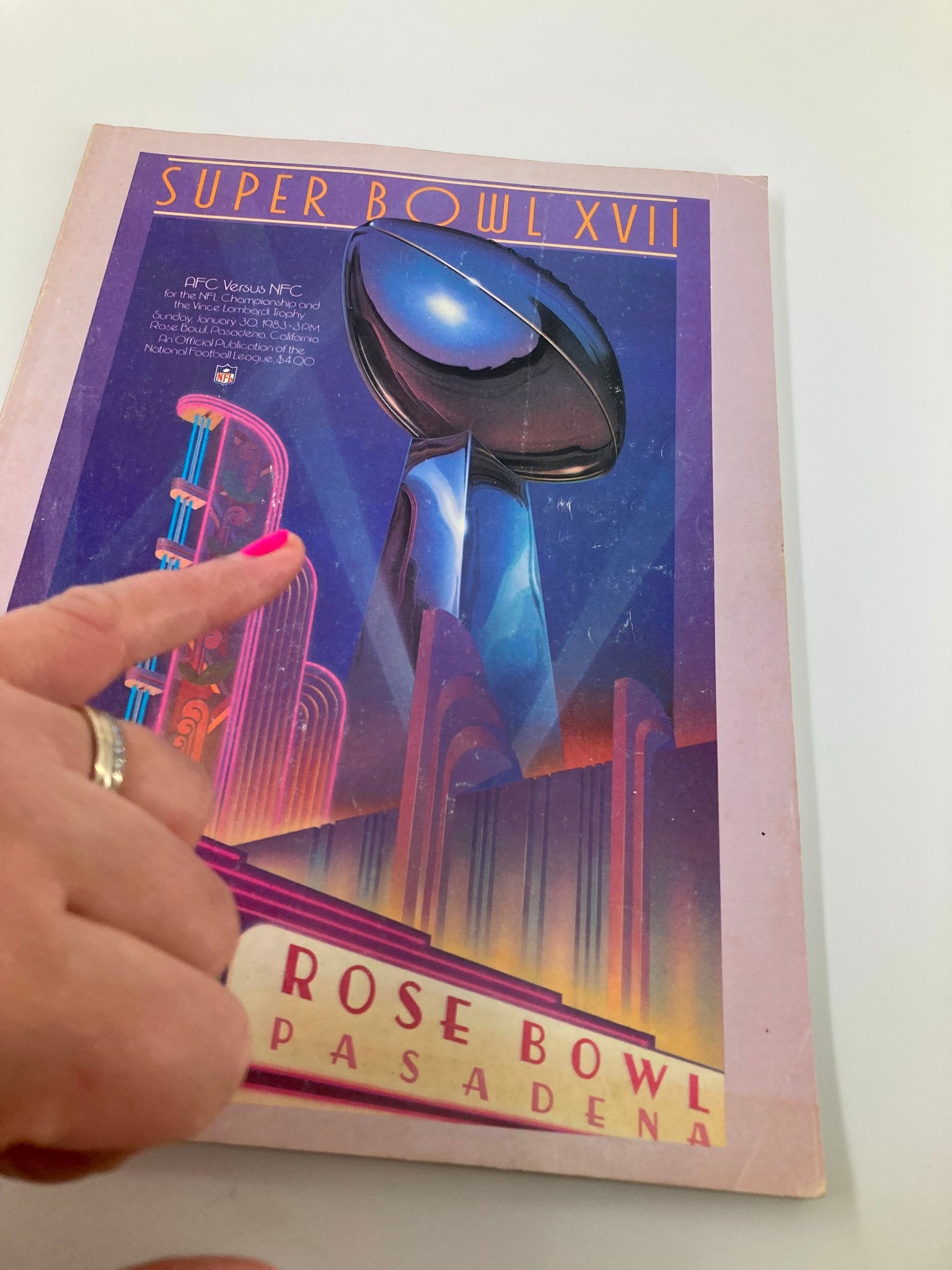 Close-up of the cover of the 1982 NFL Super Bowl XVII Magazine highlighting the AFC vs NFC match-up for the Vince Lombardi Trophy with a hand pointing to the Rose Bowl.