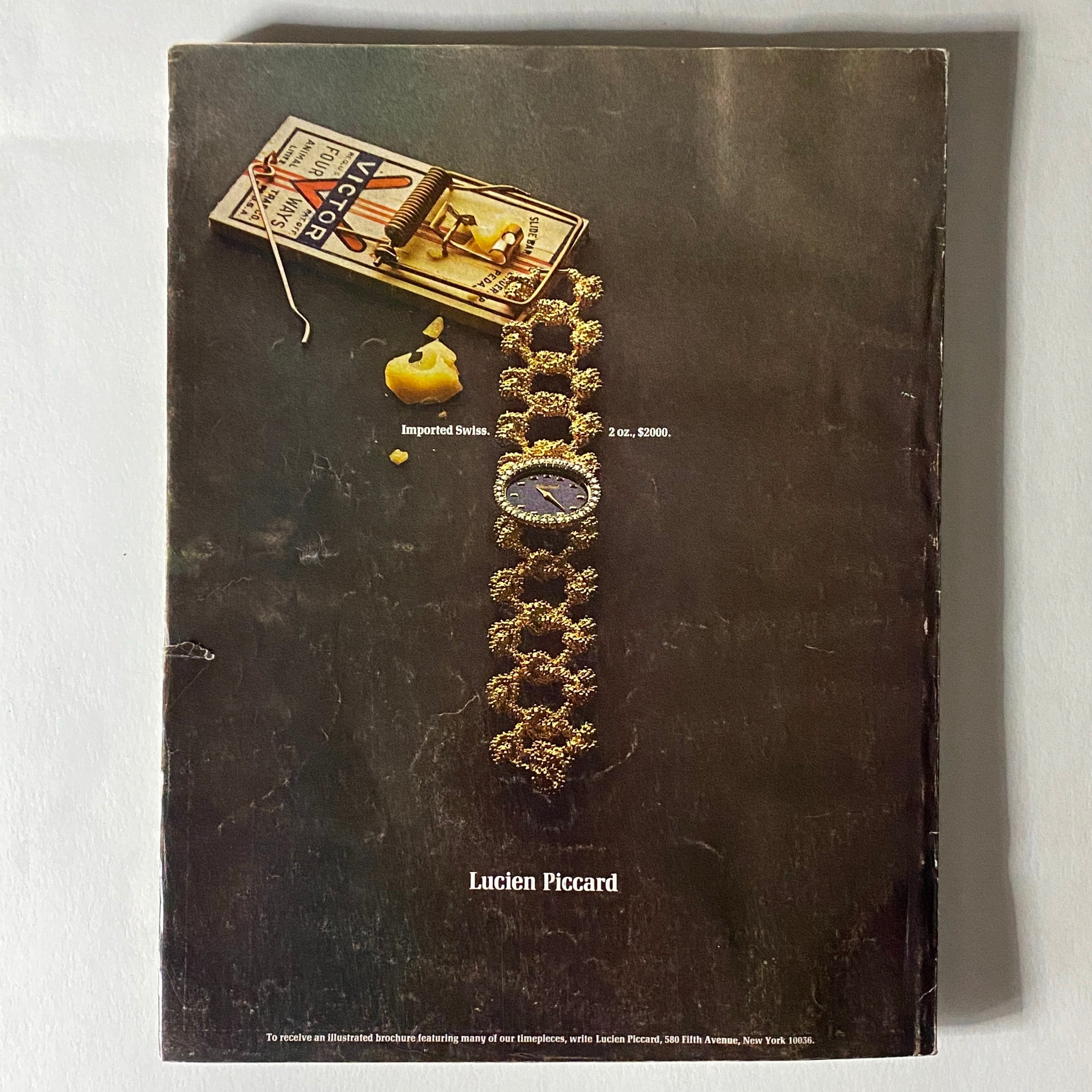 Back cover of VTG Vogue Magazine November 15, 1970 displaying an advertisement for Lucien Piccard featuring a unique watch design and a creative visual element with a mouse trap, indicative of vintage advertising style.