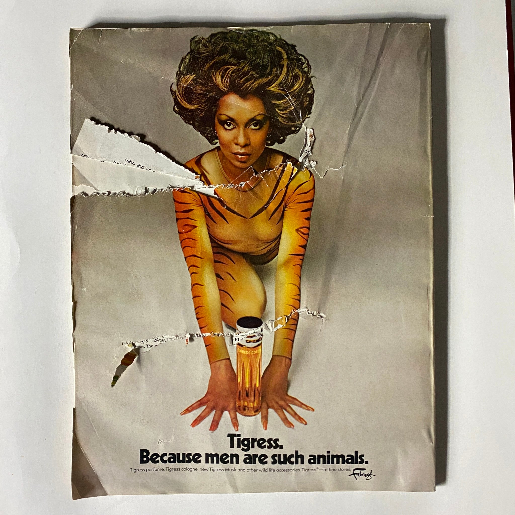 A striking vintage advertisement from the 1975 VTG Vogue Magazine featuring a model in a tiger-striped outfit promoting Tigress perfume, embodying bold 70s aesthetics.