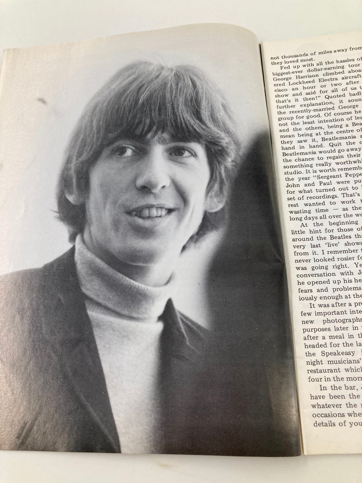 Black and white photograph of George Harrison smiling in the Beatles Book Monthly Magazine February 1986 #118, capturing a joyful moment during a discussion about their music.