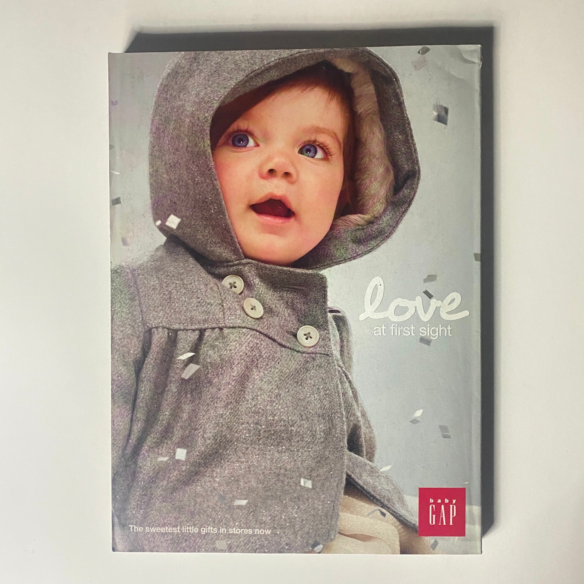 Gap Catalog featuring a cute child model in a cozy coat, promoting the 'love at first sight' theme with festive decor.