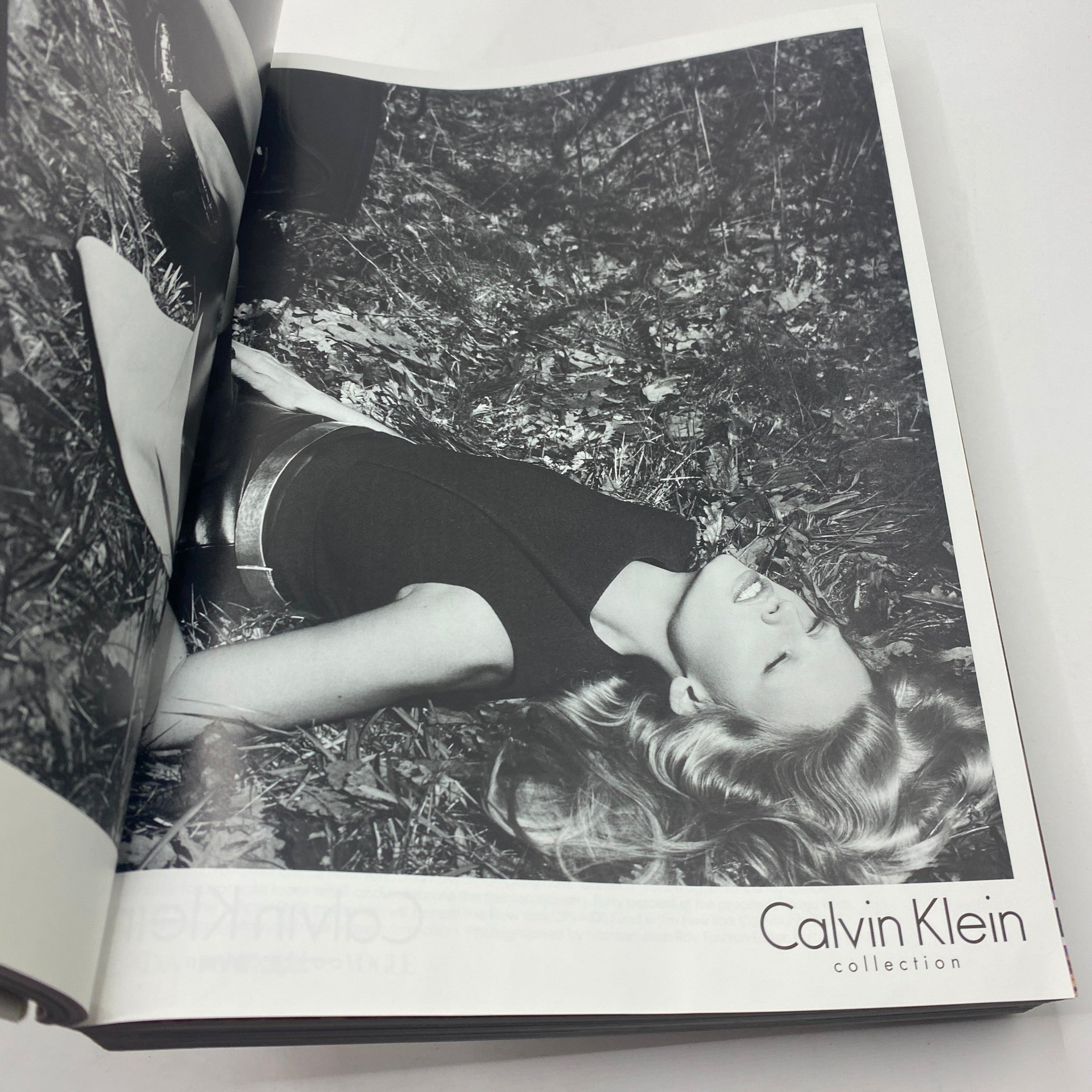 Fashion advertisement from Vogue Magazine September 2012 showcasing the Calvin Klein collection, featuring an elegant model lying in nature, illustrating a chic, relaxed style.