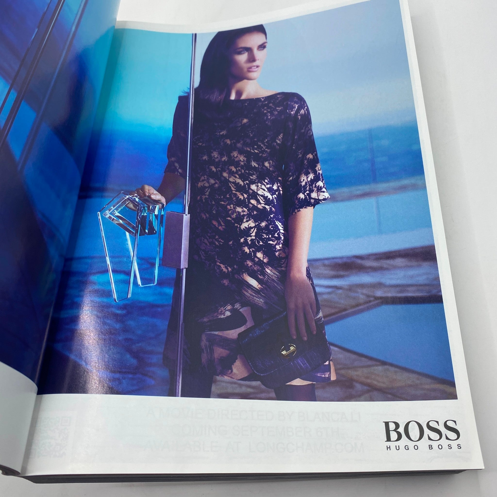 Hugo Boss advertisement from Vogue Magazine September 2012, displaying a stylish model wearing a floral dress, holding a handbag, set against a modern backdrop, emphasizing luxury fashion.