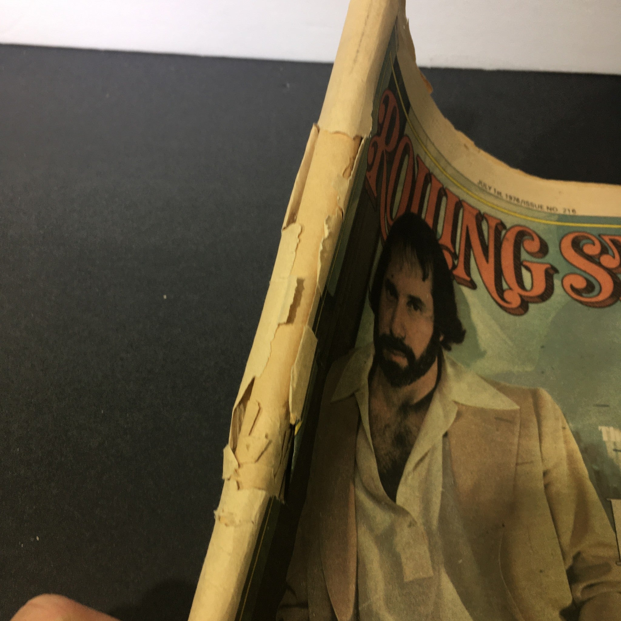 Side view of the July 1, 1975 Rolling Stone magazine showing wear and tear typical for its age, including cover damage, highlighting its vintage character.