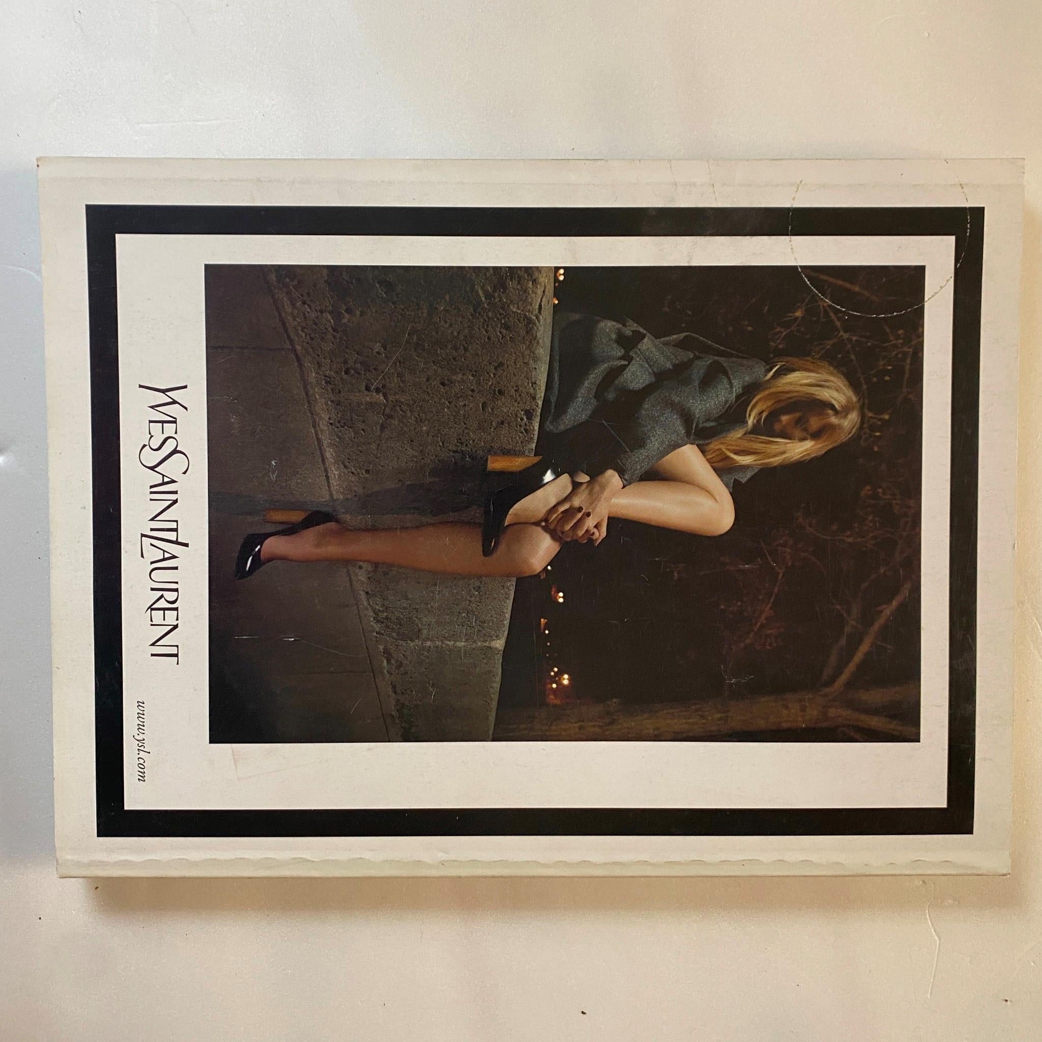 Yves Saint Laurent advertisement from Elle Magazine October 2007 featuring a stylish model dressed in formal attire, sitting against a dark urban backdrop. This image represents luxury fashion and personal style trends of the late 2000s.