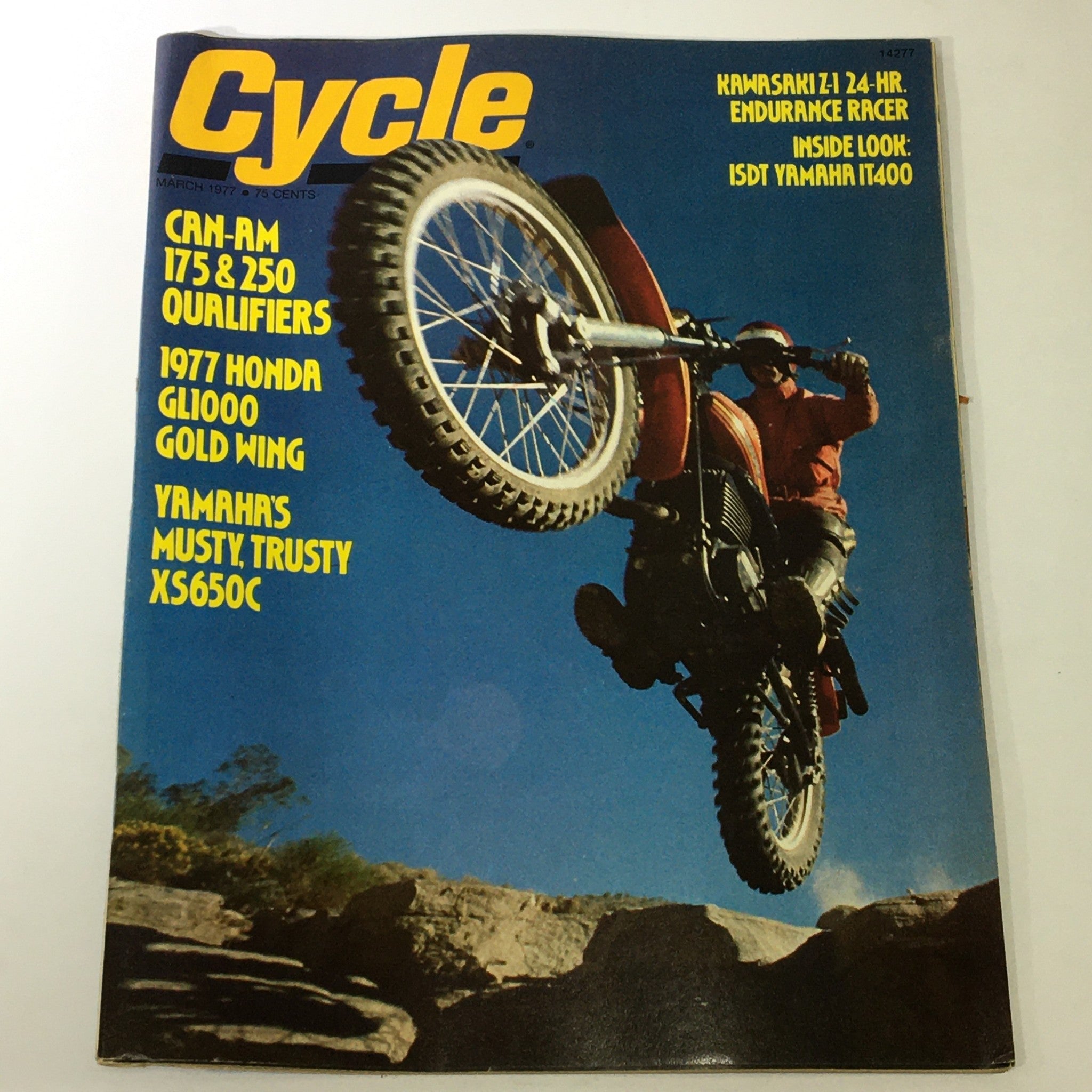 Cover of VTG Cycle Magazine March 1977 featuring Can-Am 172 & 250, Honda GL1000, Yamaha IT400, showcasing a motorcycle rider performing a stunt with a dirt bike on rocky terrain.