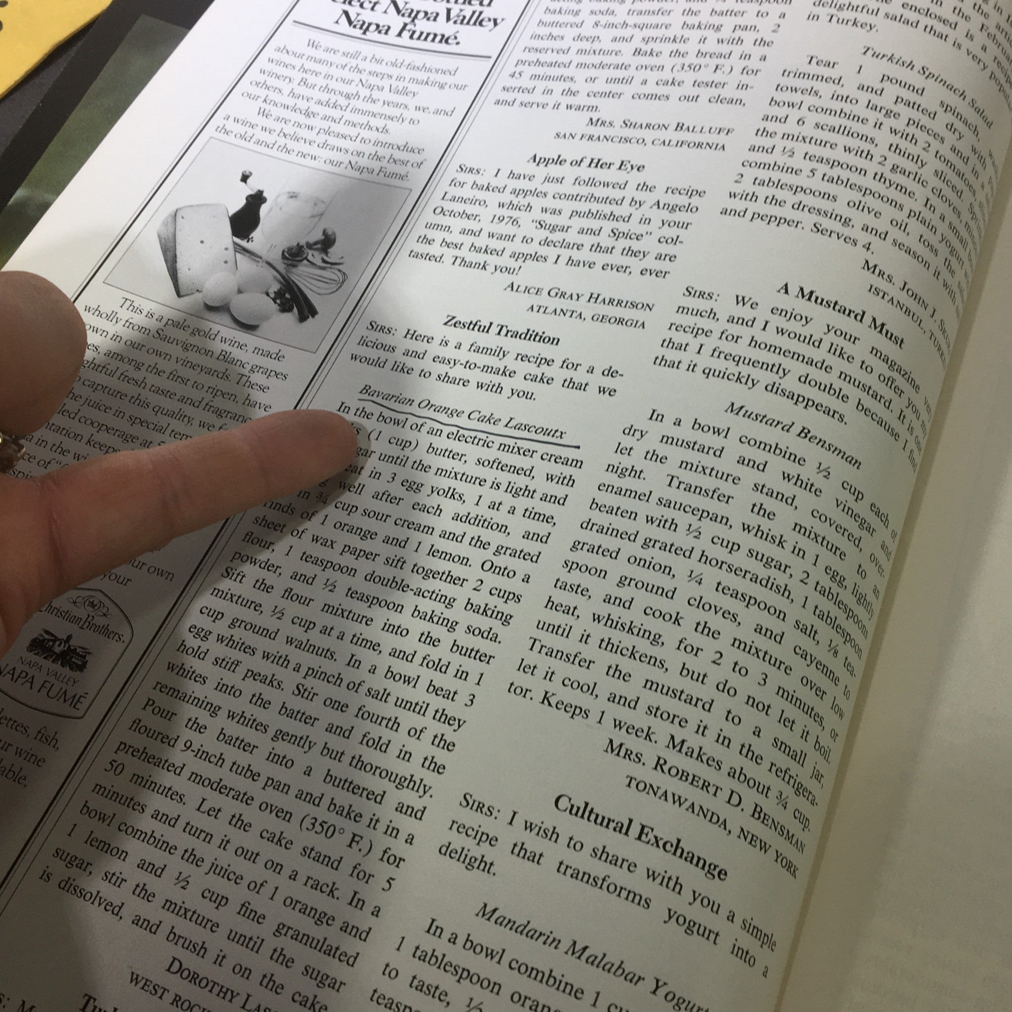 Close-up of a page from the VTG Gourmet Magazine February 1977 featuring recipes and cooking tips, showcasing a finger pointing at a recipe for Bavarian Orange Cake Lazawti.