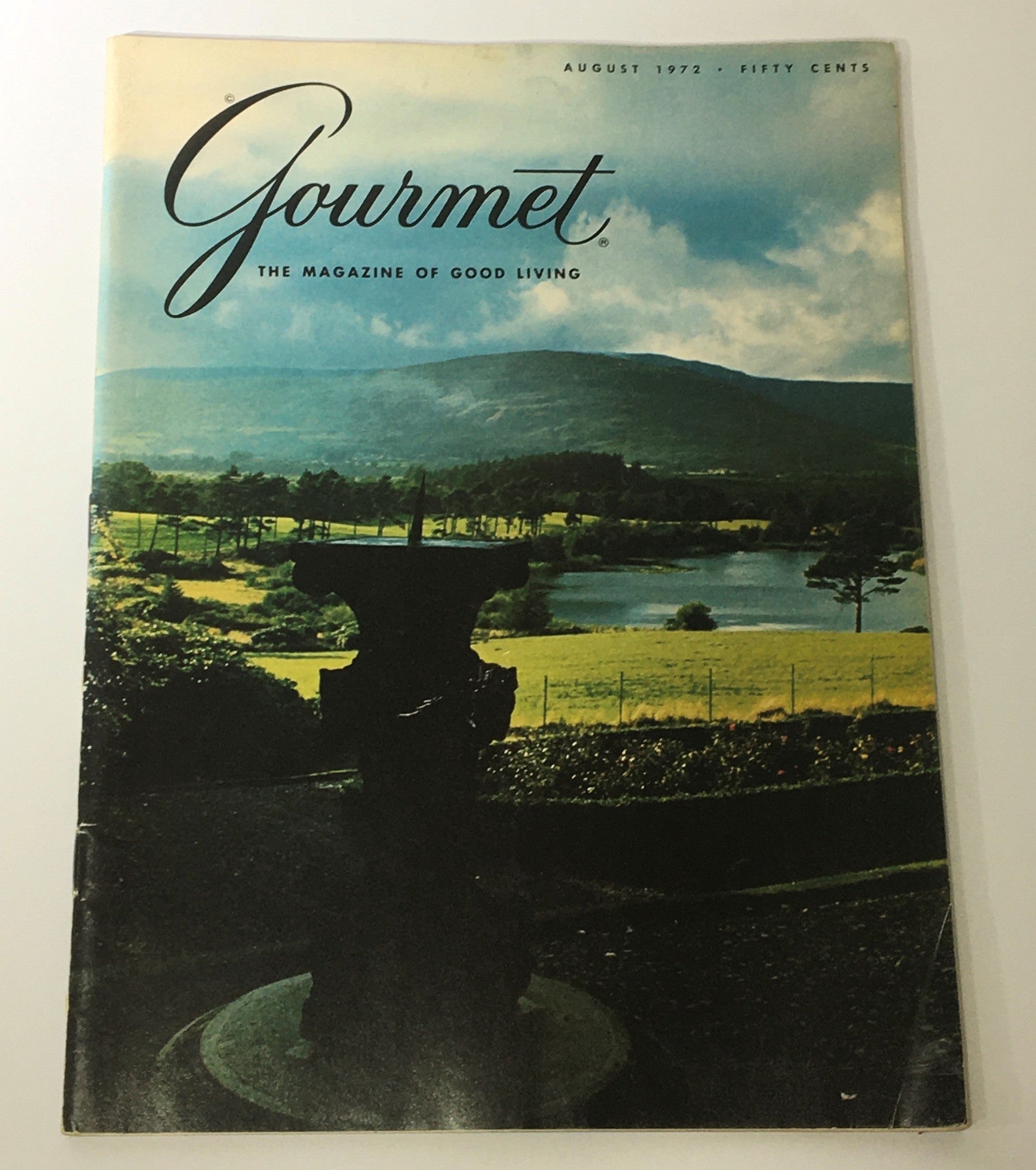 Cover of VTG Gourmet The Magazine of Good Living August 1972 featuring a scenic landscape with a fountain and rolling hills, highlighting themes of home cooking and sustainability.