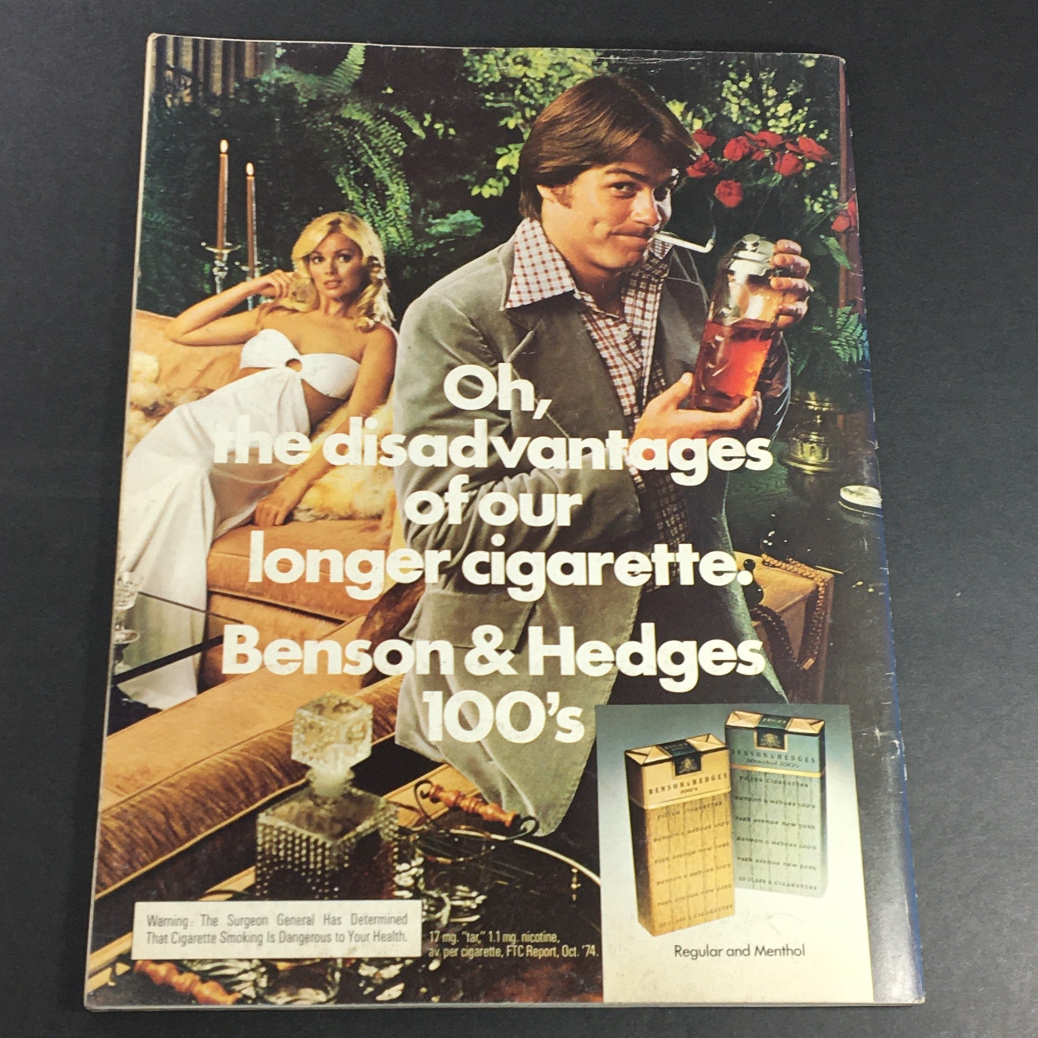 Vintage advertisement for Benson & Hedges cigarettes featuring a stylish man in a suit holding a cocktail, accompanied by a glamorous woman, illustrating 1970s lifestyle elements.