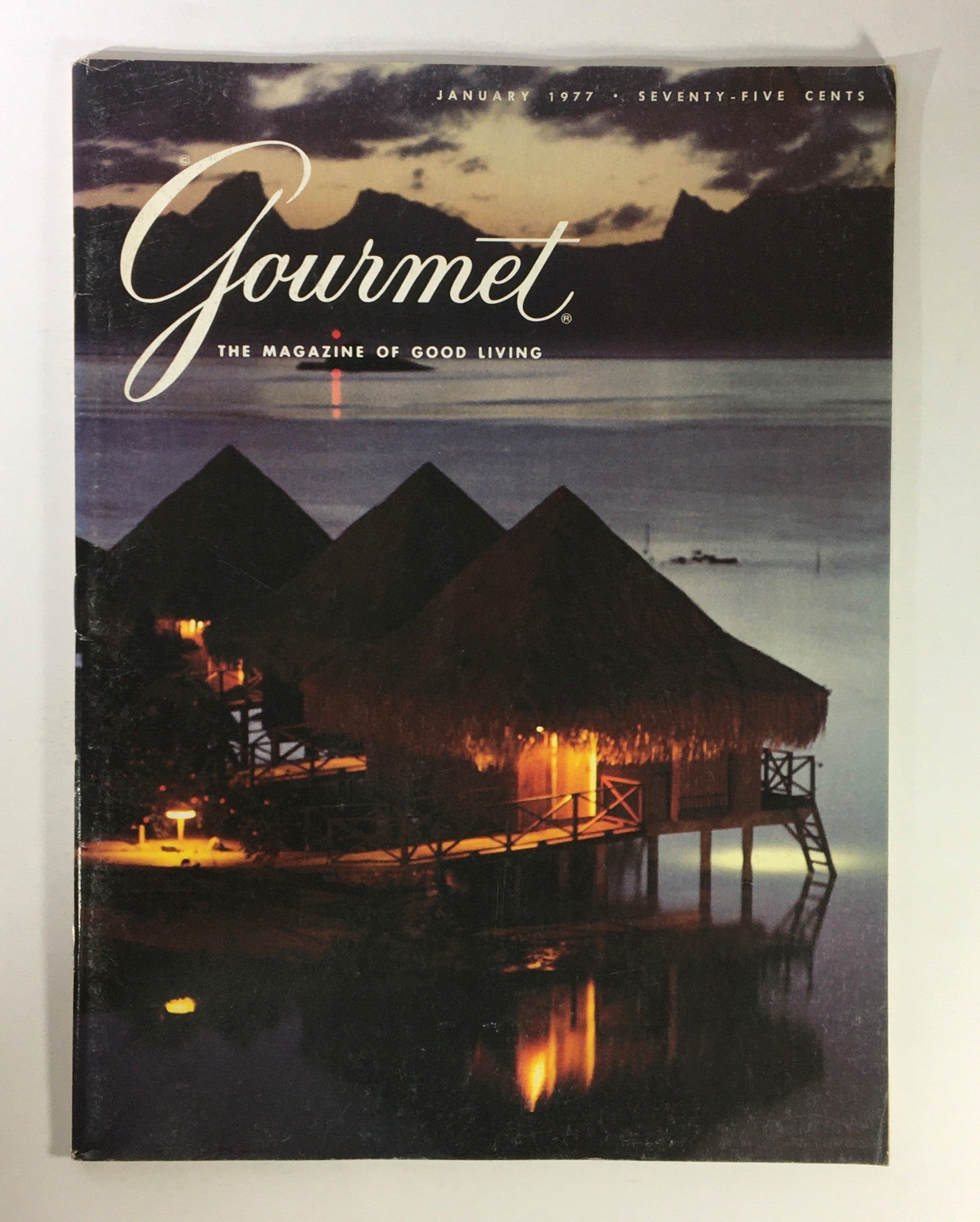 Cover of VTG Gourmet The Magazine of Good Living January 1977, showcasing beautiful waterfront huts illuminated at night, symbolizing French culinary culture and lifestyle.
