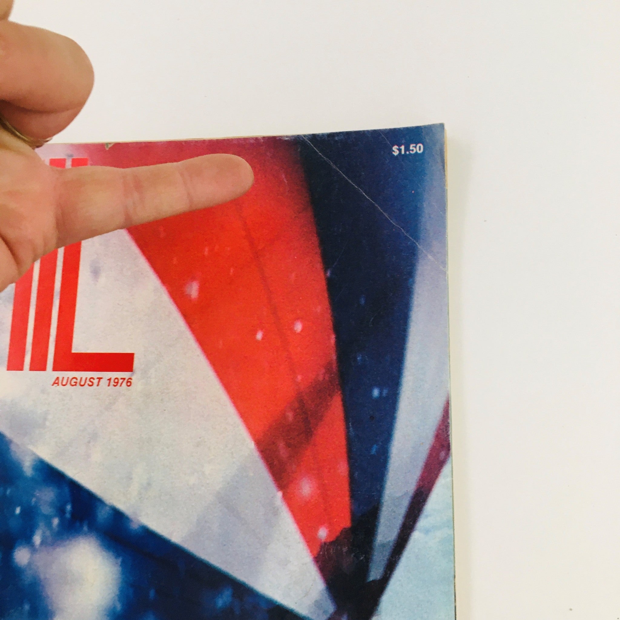 Close-up view of the cover of Sail Magazine August 1976, highlighting the title 'The Unmaking of a Racing Sailor' by Mimi Dyer, with a finger pointing to the magazine title and price.