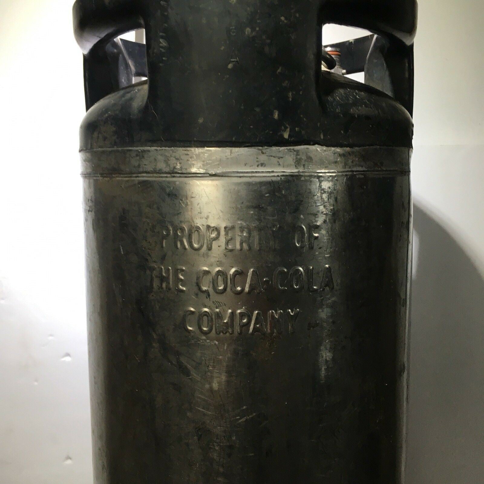 Close-up of the embossed text on Vintage COCA COLA Keg Syrup 5 Gallon indicating it is the property of The Coca-Cola Company.