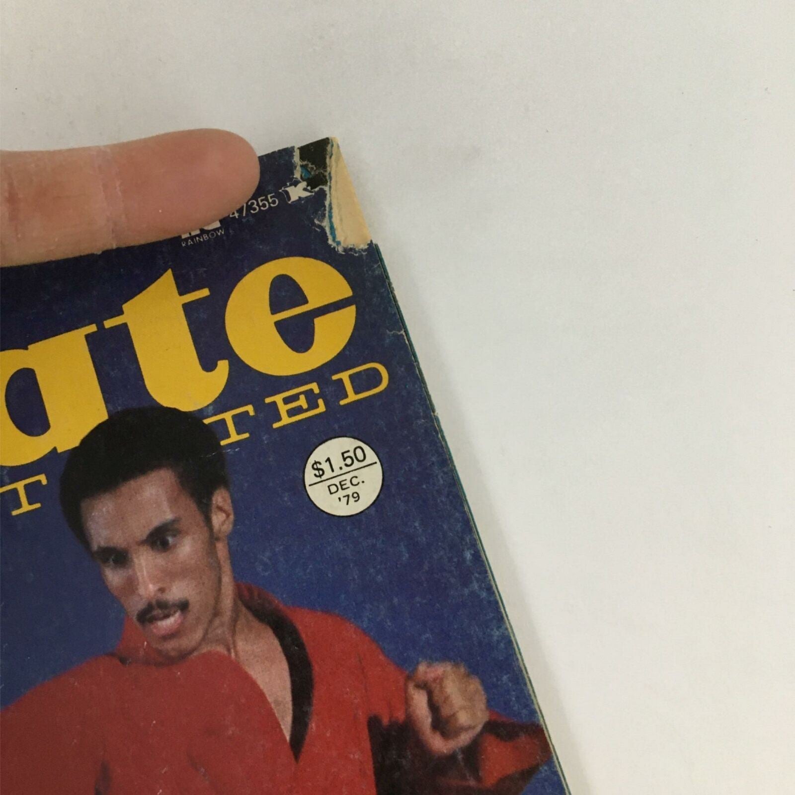 Detail of the top of Karate Illustrated Magazine December 1979, displaying the price tag and publication date along with worn edges, representing its vintage condition.